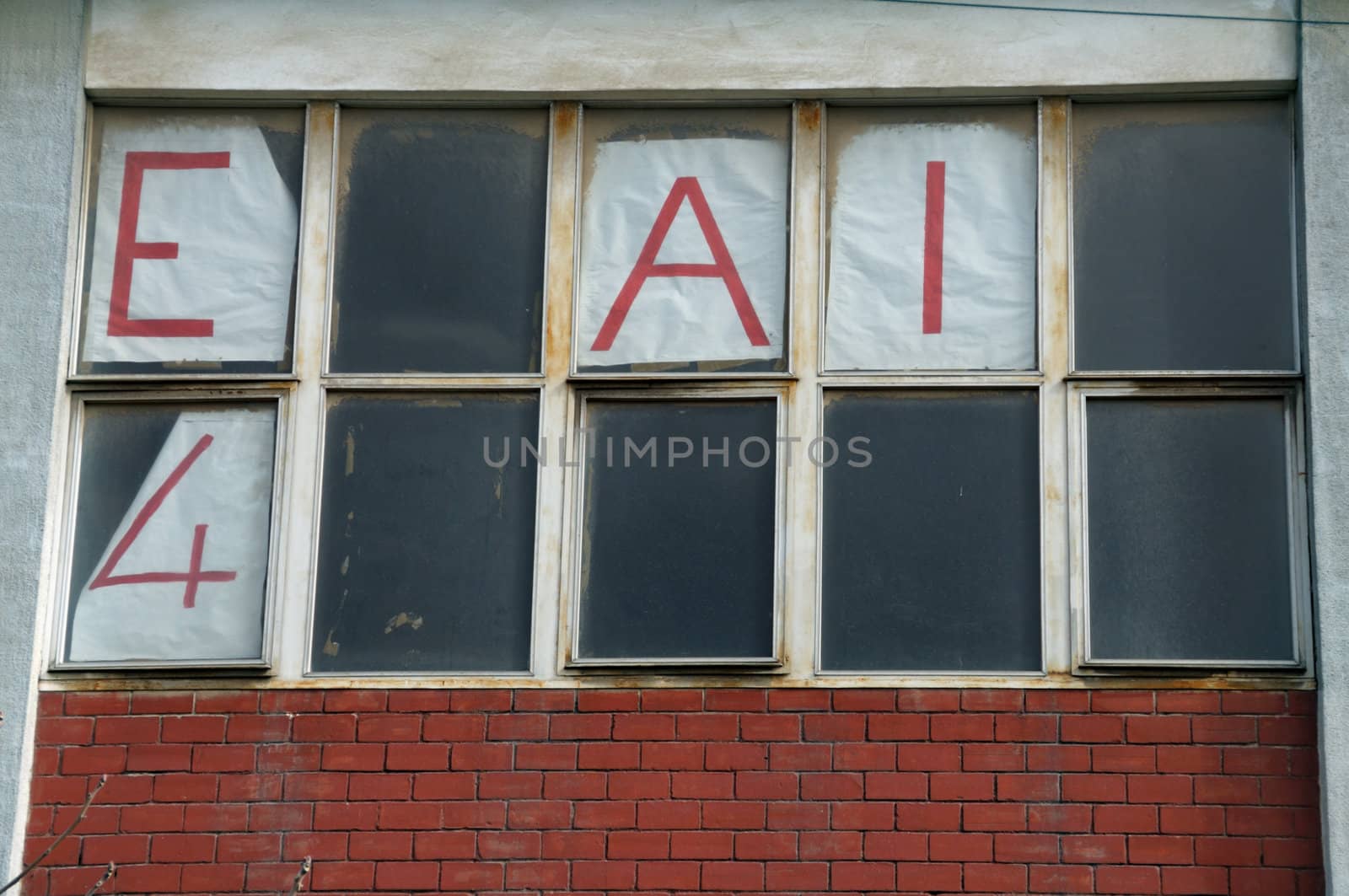 Forgotten crumbling for rent sign on dusty windows of abandoned building.