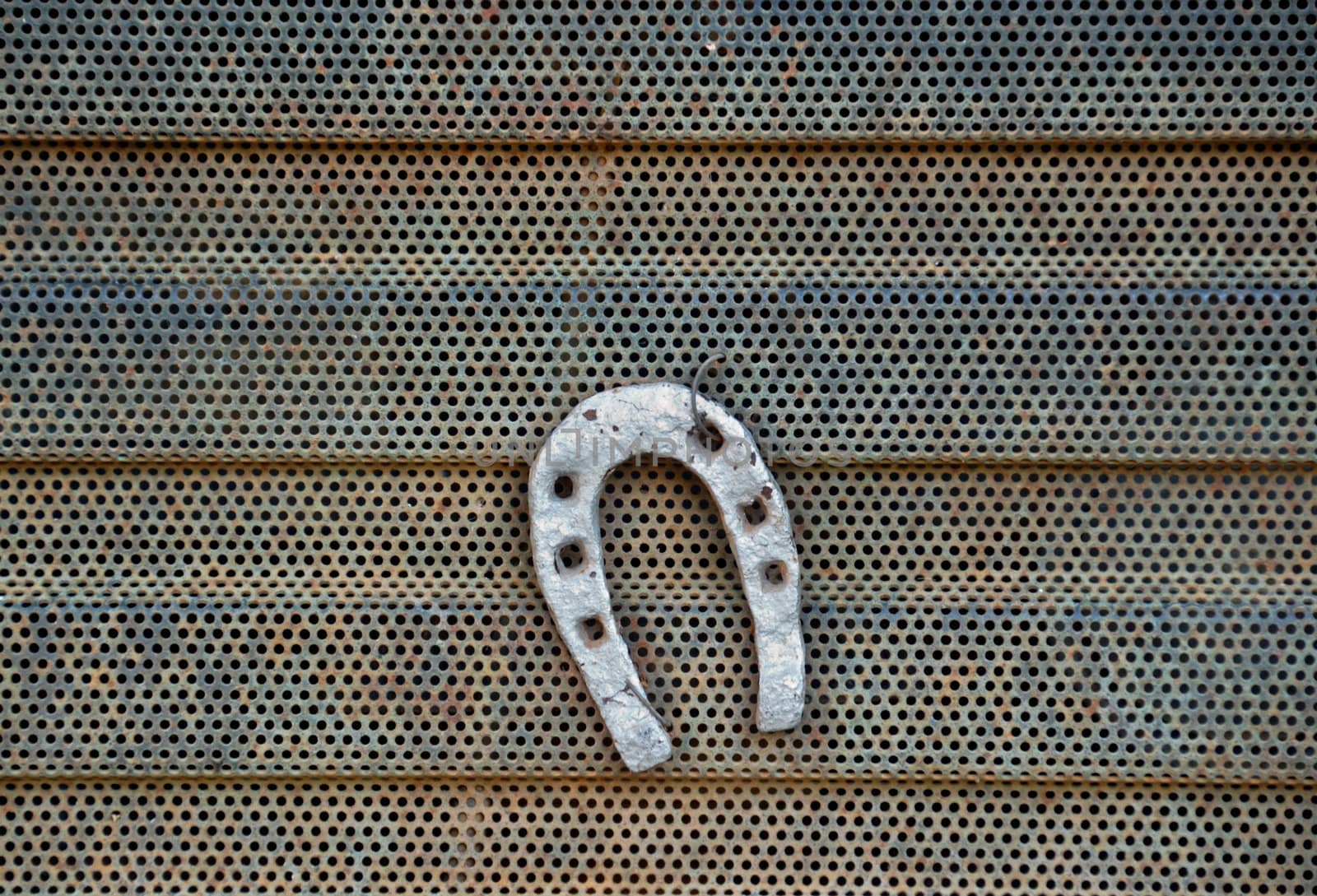 Horsheshoe on rusty metal radiator grill detail.