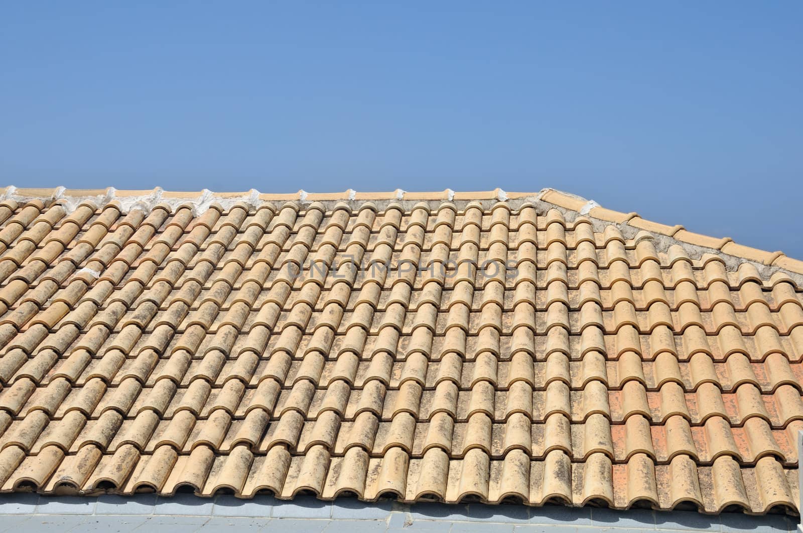 Sloped ceramic tiles roof background. Traditional house against blue sky.