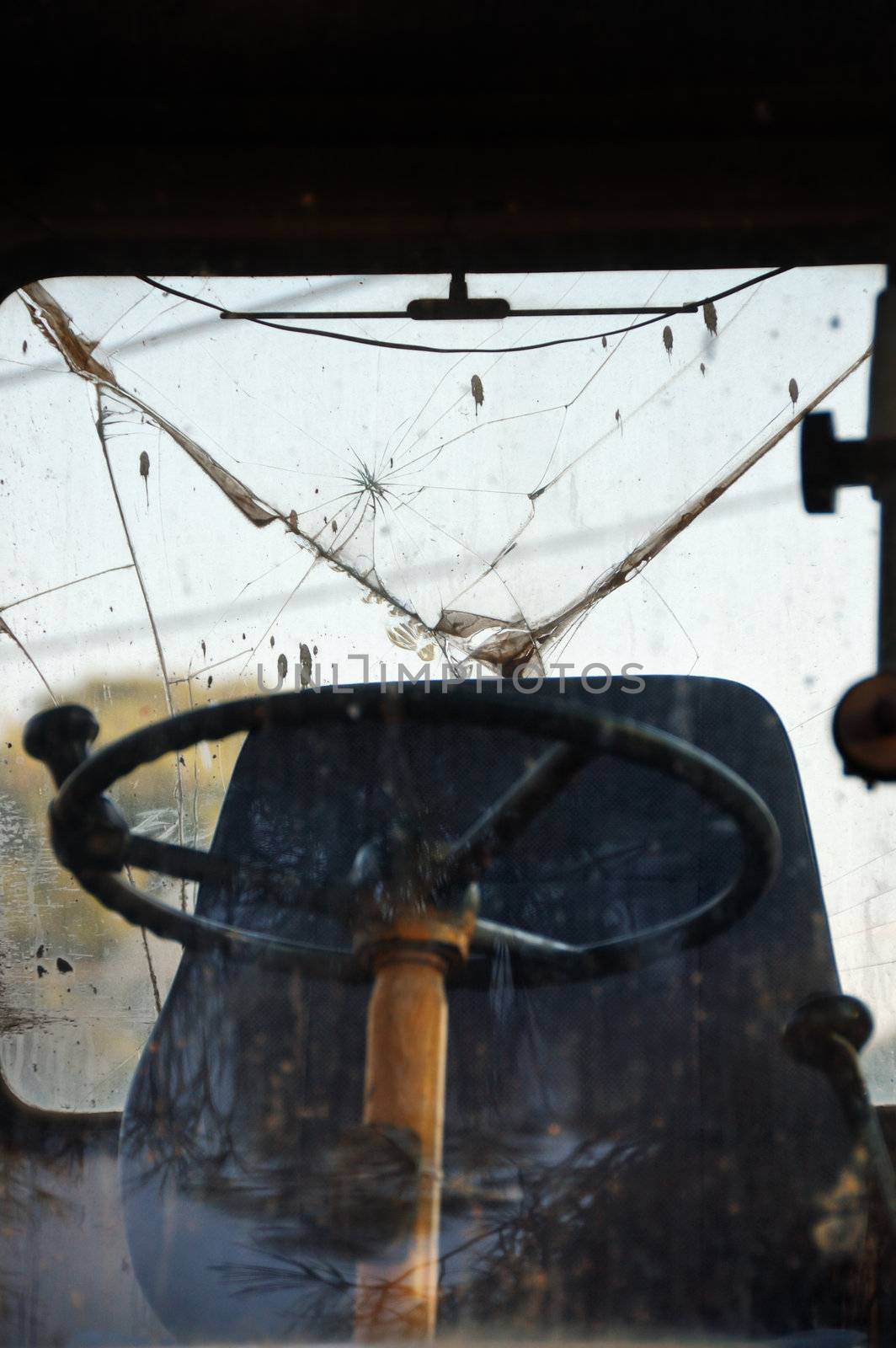 Steering wheel and driver cabin of industrial machinery. Light reflections on broken windscreen glass.