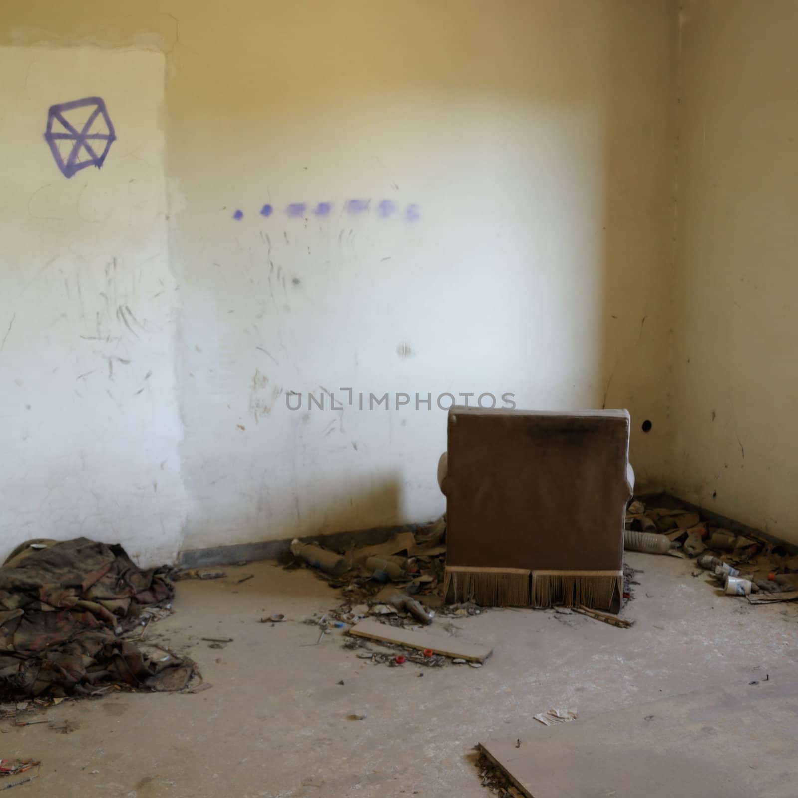 Armchair facing the wall in abandoned house. Drug use paraphernalia on the floor.