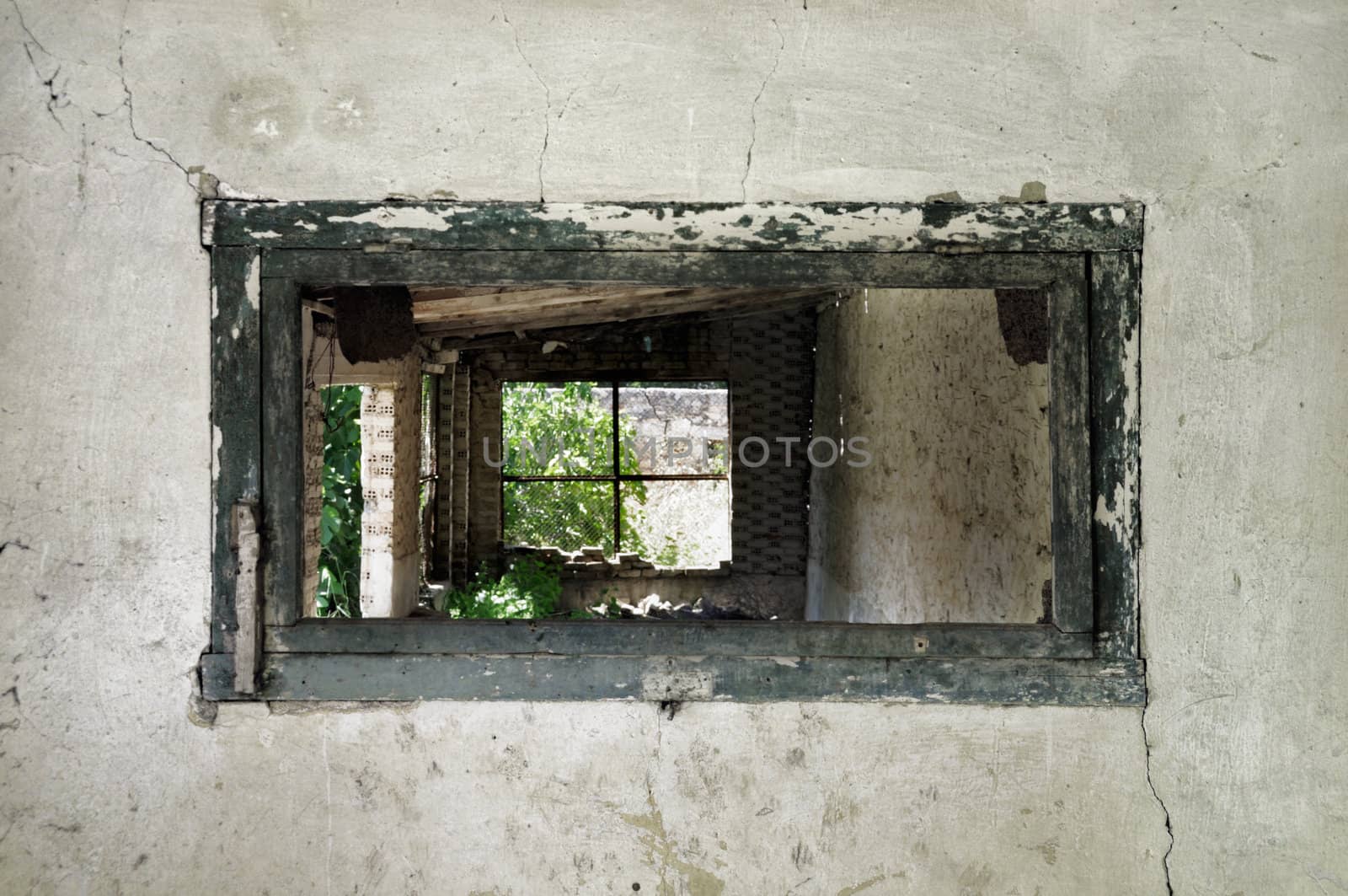 Wooden weathered window frame and crumbling wall in abandoned building.