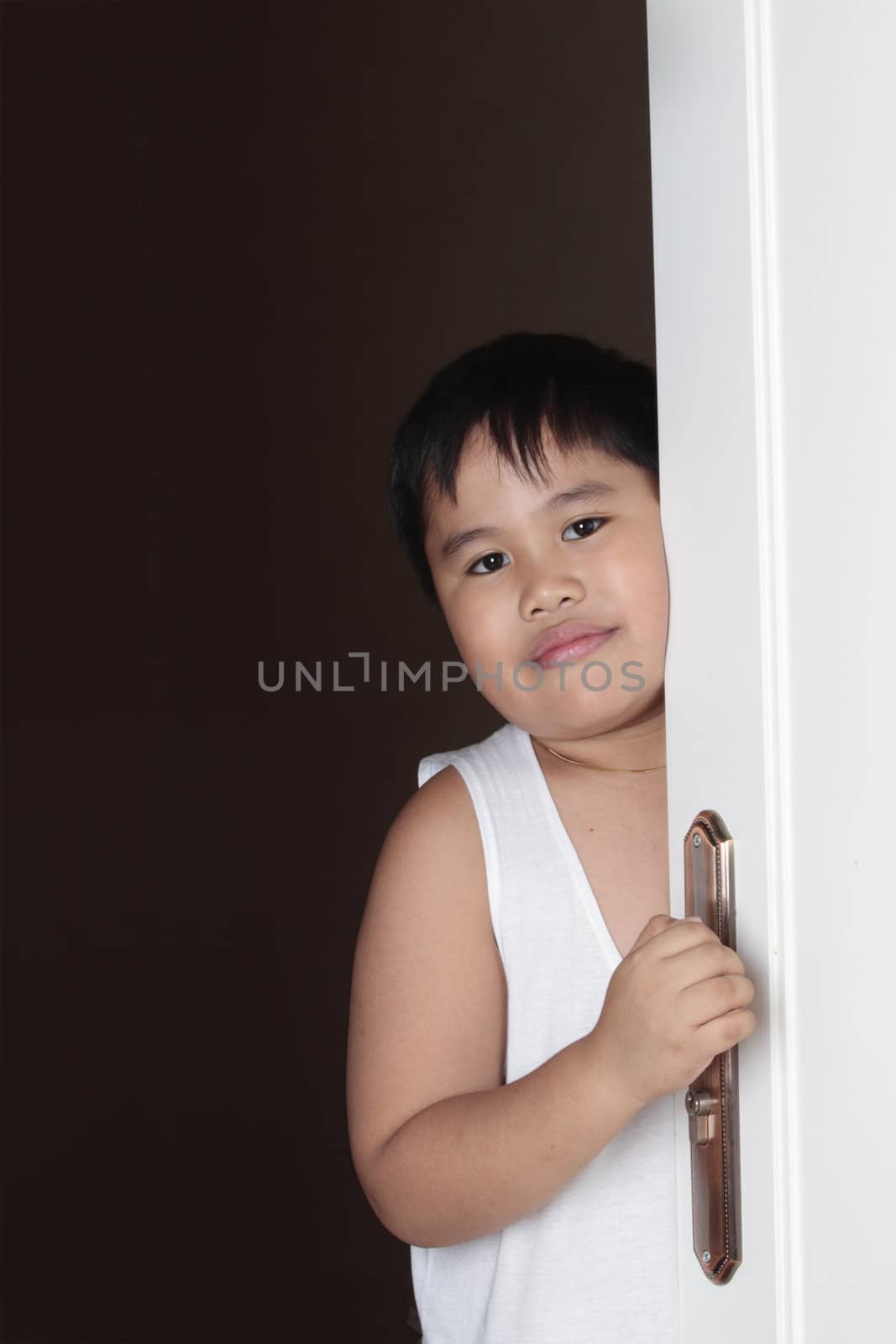 smiling happy asian boy looking throught the door