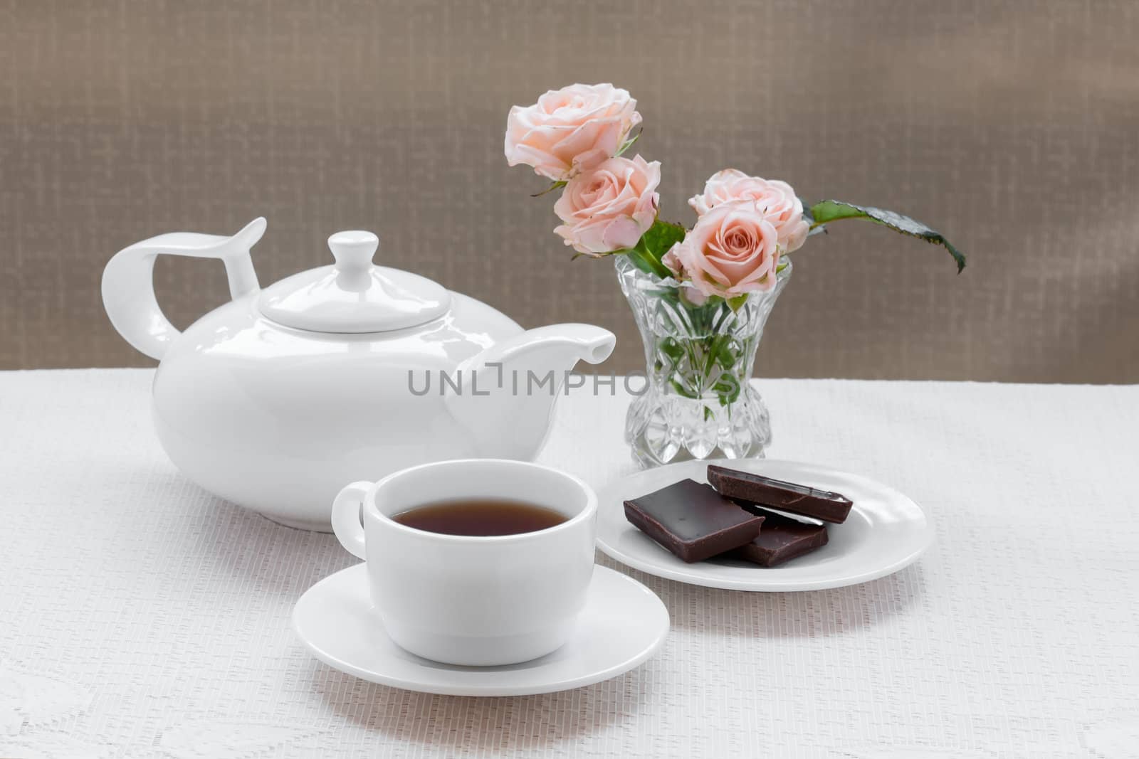 teapot, cup, roses, and chocolate on a plate