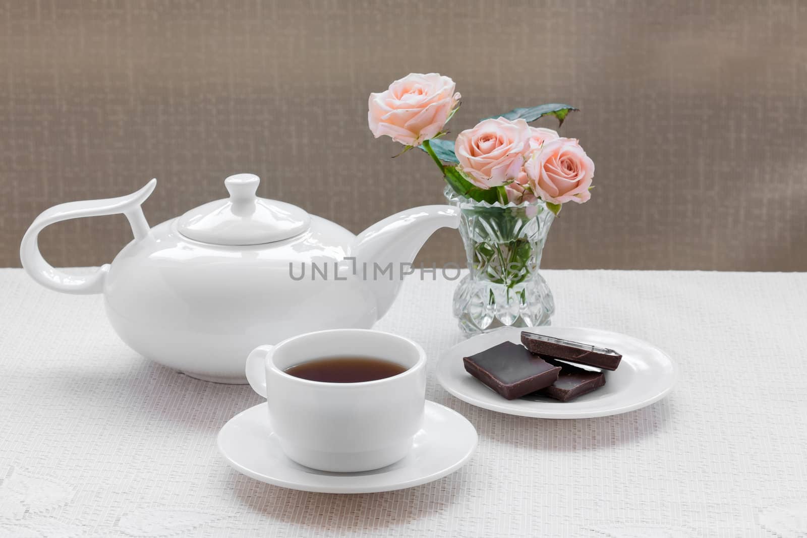 teapot, cup, roses, and chocolate on a plate