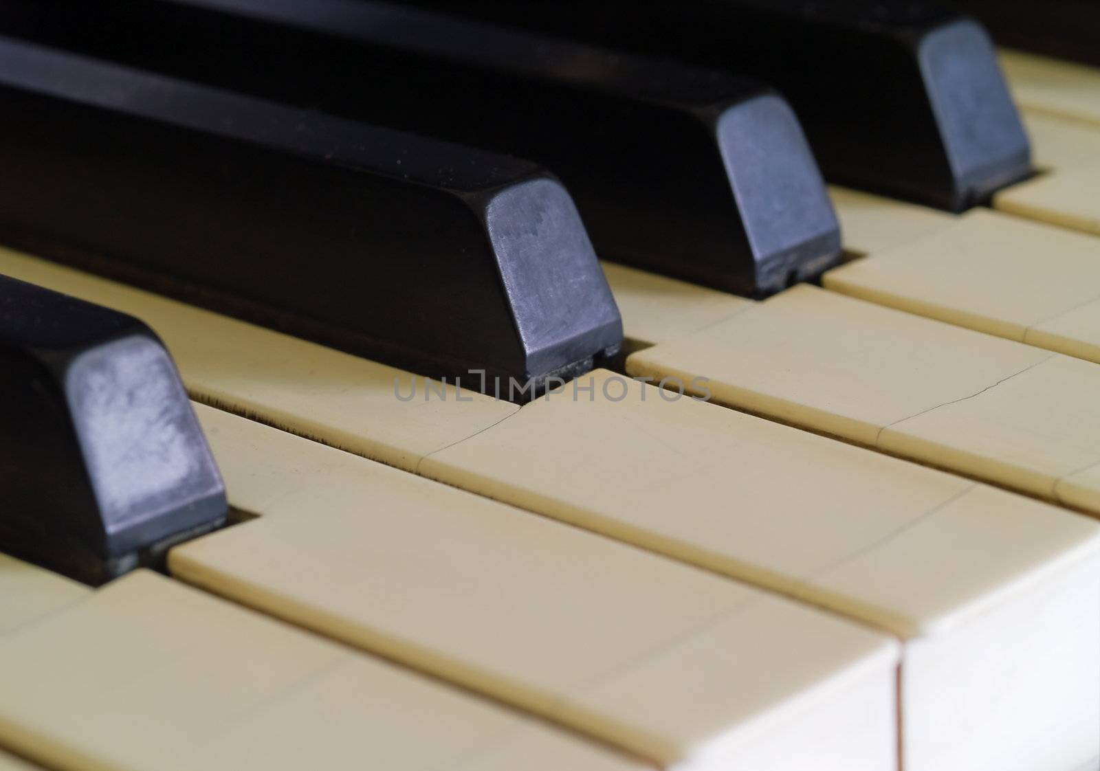 Piano keys of a very well loved and often played piano showing some wear and cracking.