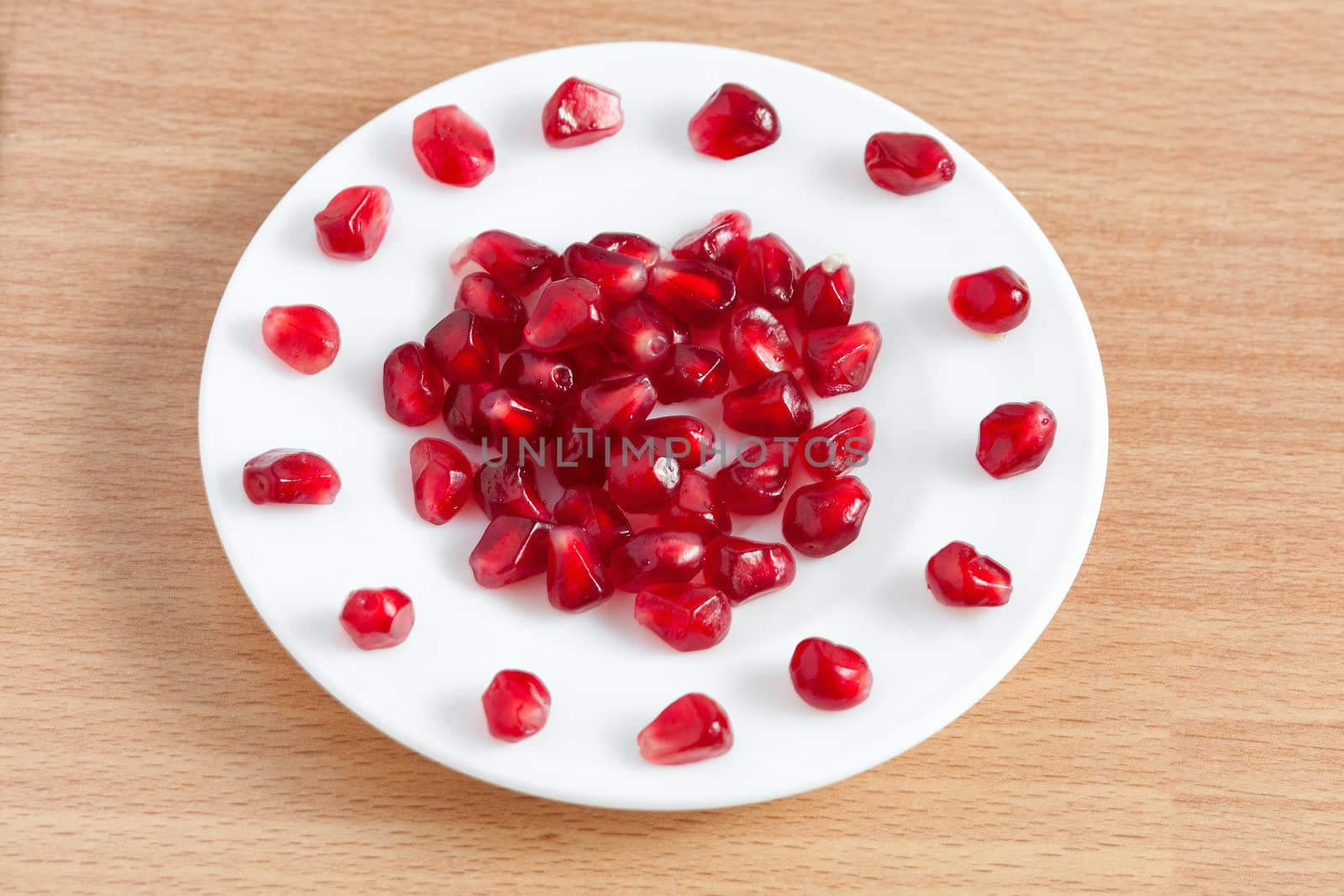 pomegranate seeds on a plate by sfinks
