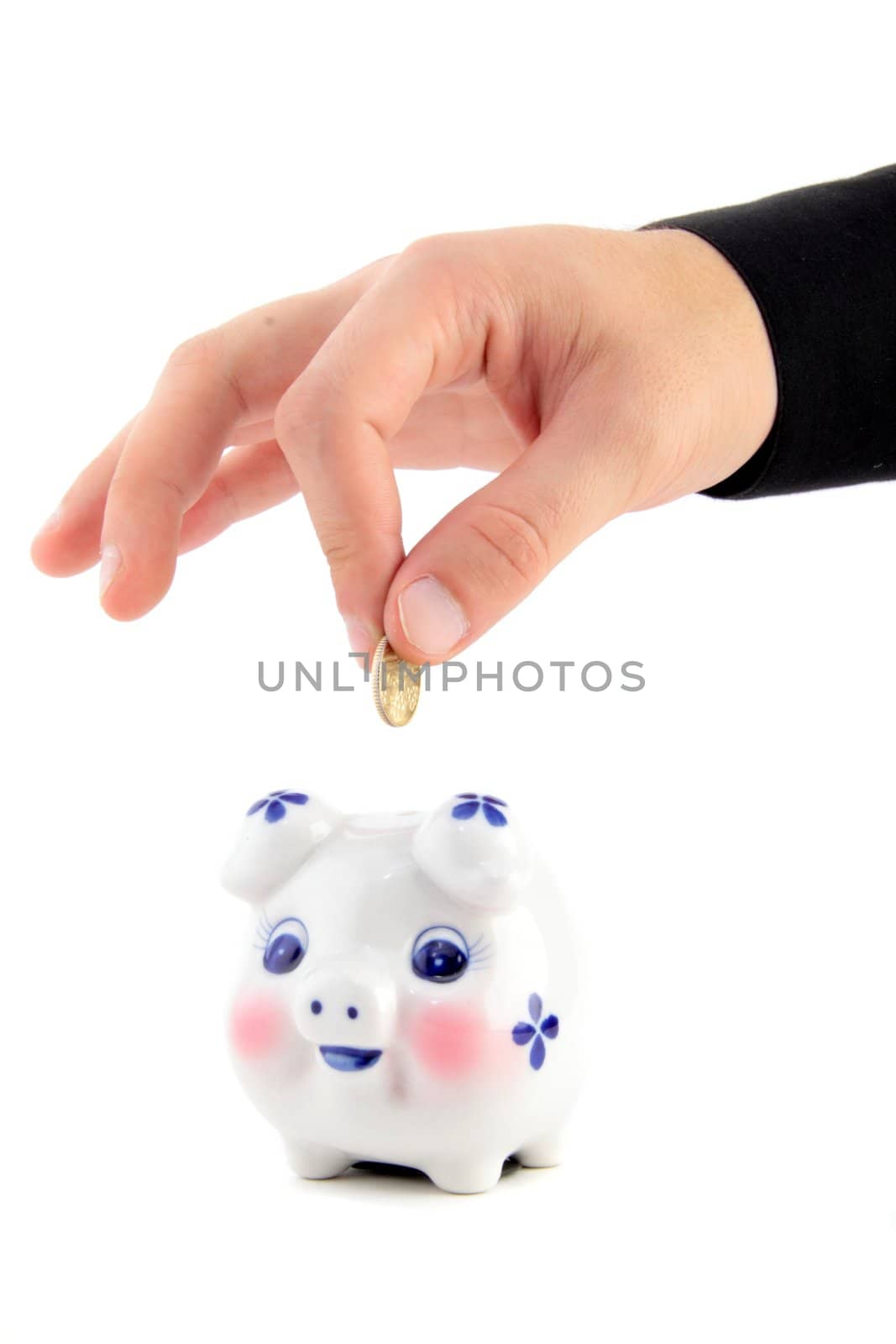 Hand inserting coin into piggy-bank isolated on white