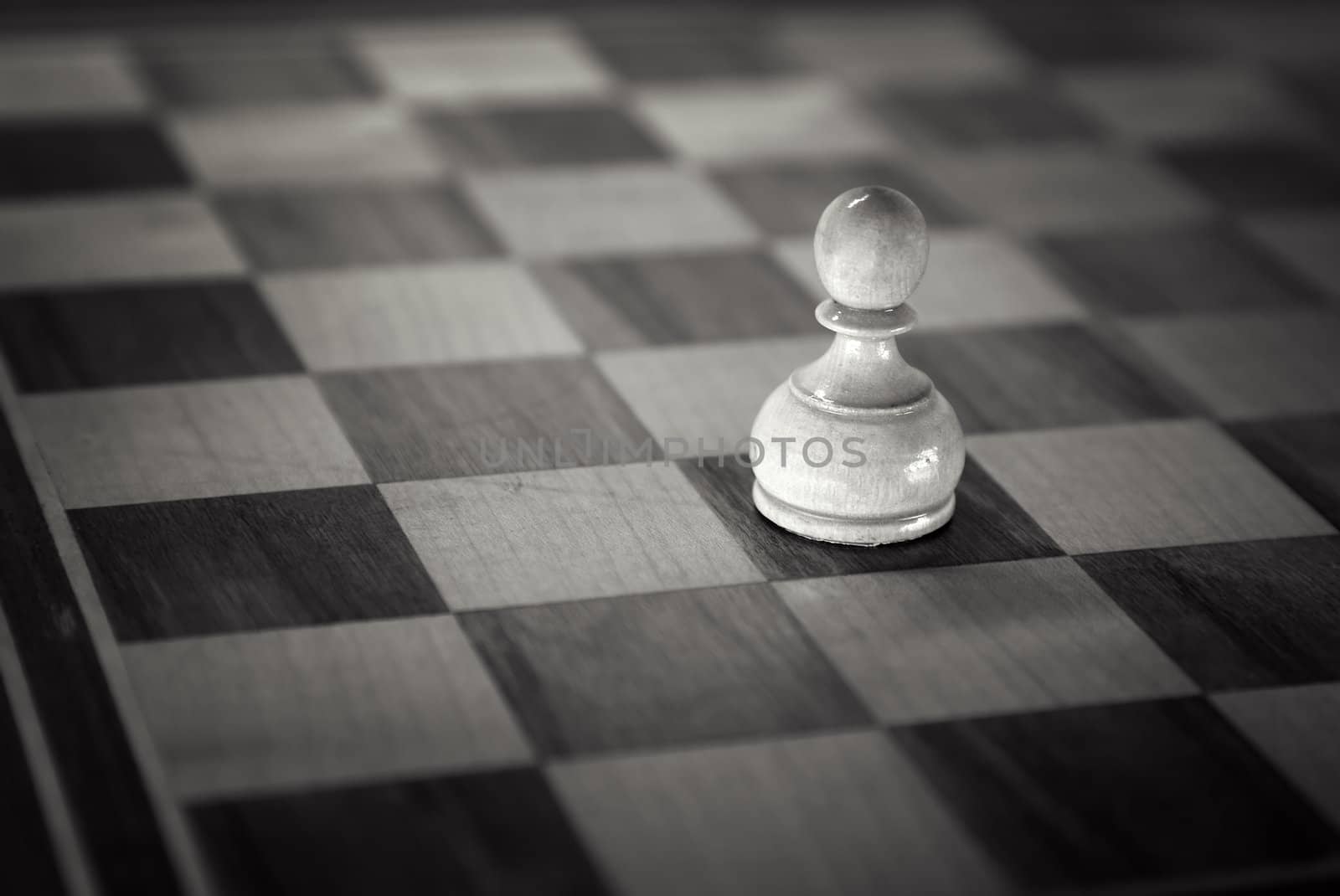 White pawn down on the chessboard . Black and white retro toned photo with shallow DOF and space for your text