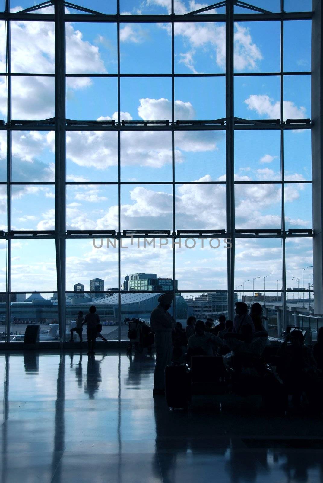 People waiting at the international airport terminal, bright blue sky outside