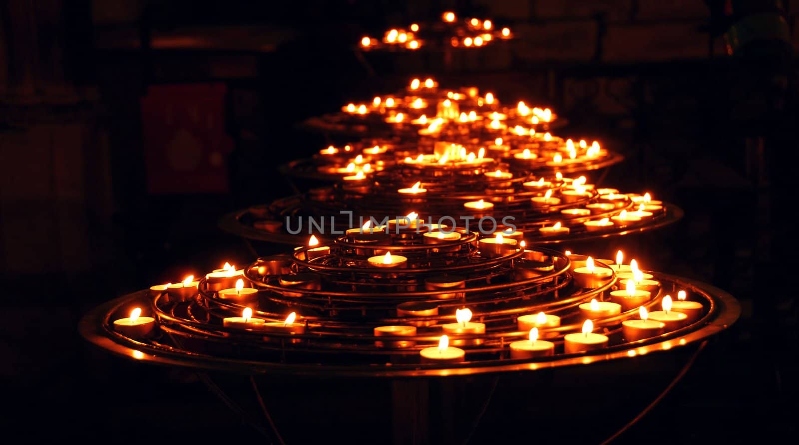 Rows of burning candles inside a cathedral