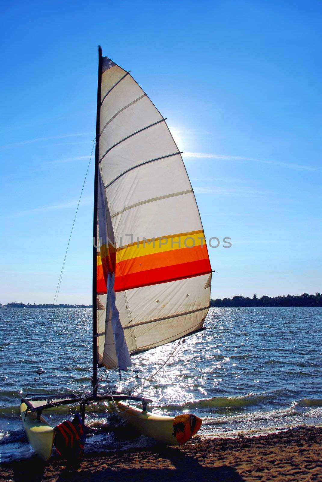 Catamaran on a beach with backlit sail