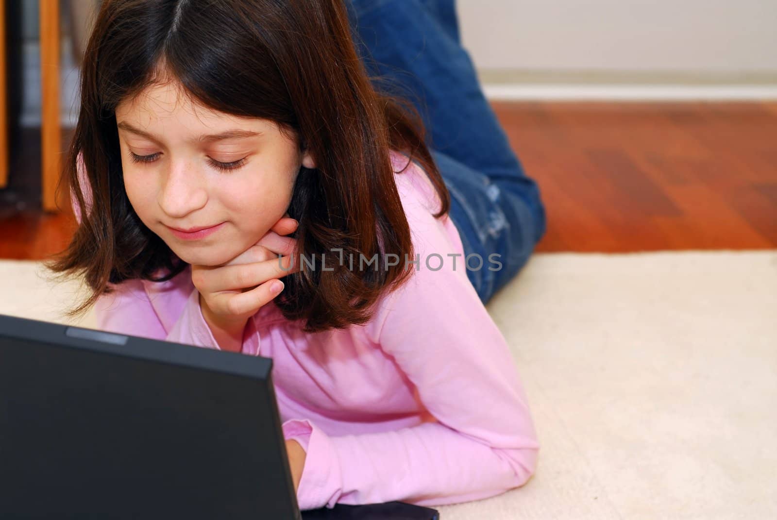 Portrait of a young girl lying on the floor and looking into computer