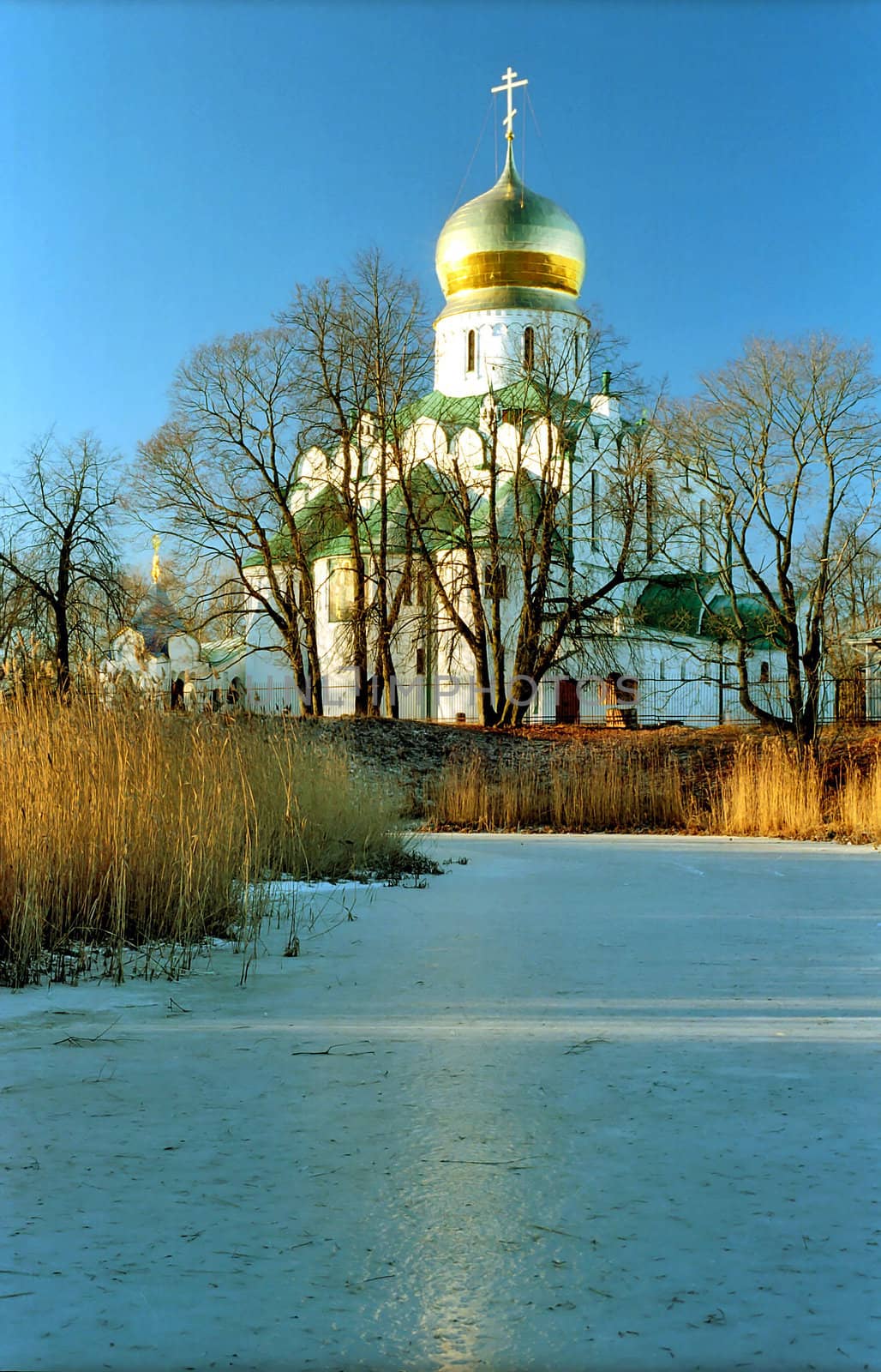 Russian church near iced pond with reflection of golden cupola