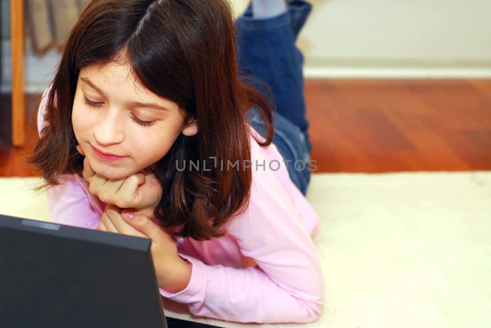 Young girl lying on the floor with portable computer