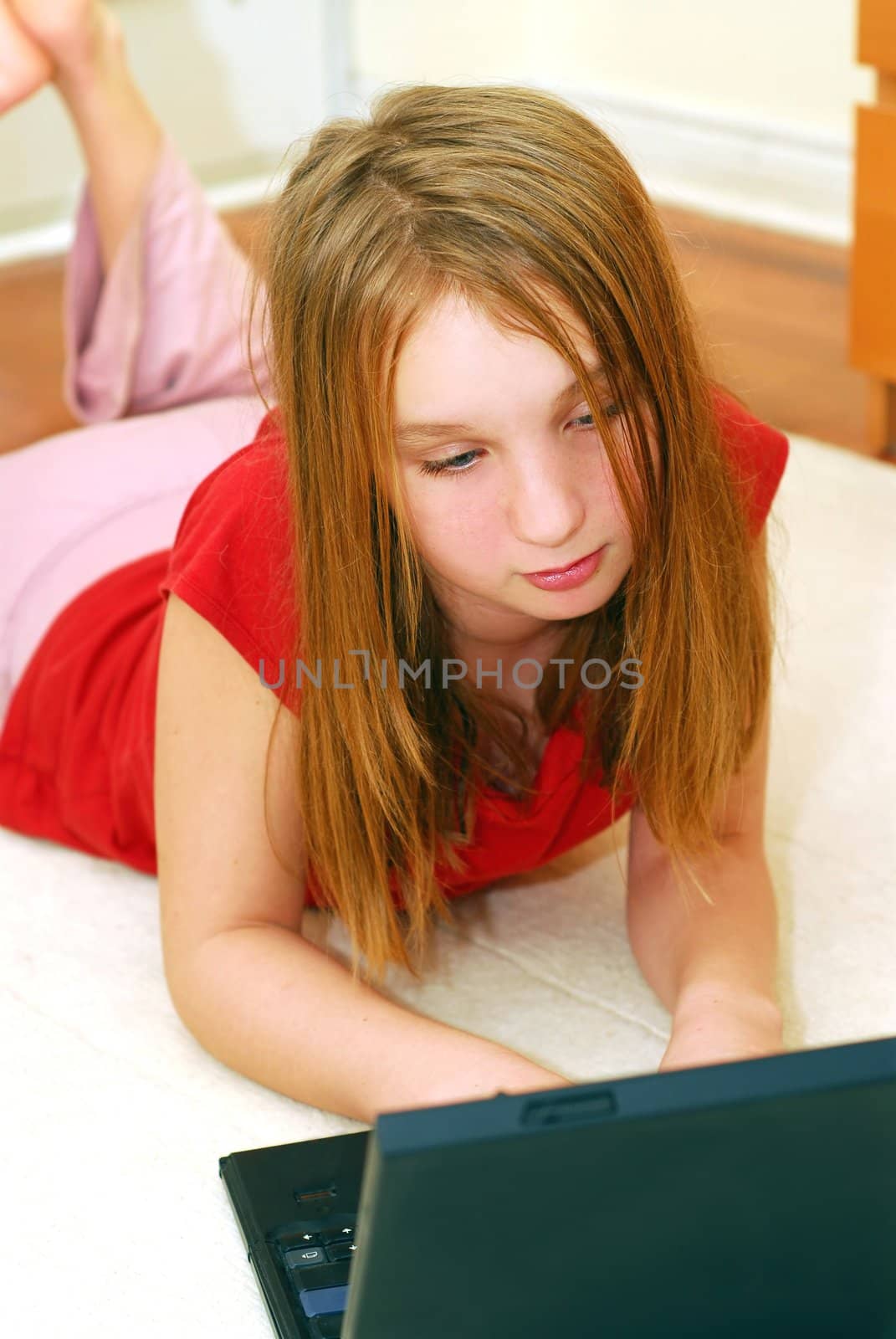 Young girl lying on the floor with portable computer