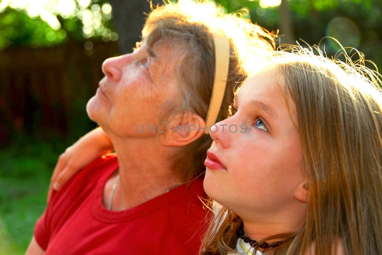 Portrait of grandmother and granddaughter in summer park looking up