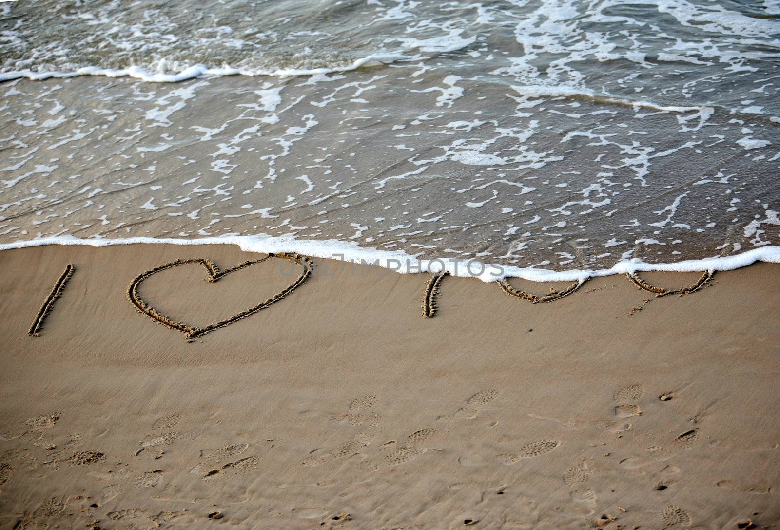 Words about love written on wet sand