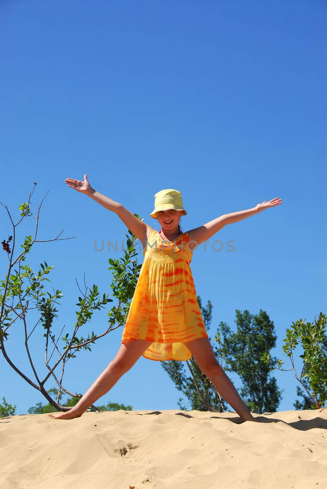 Young girl standing on top of a sand dune