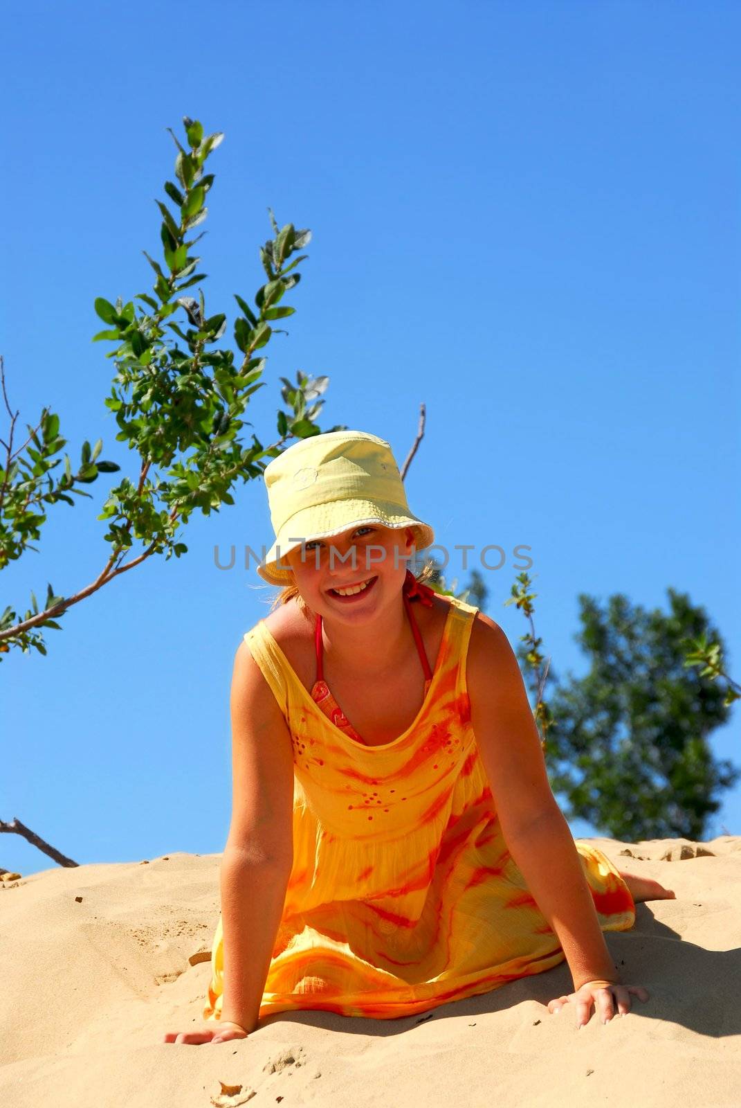 Young girl sitting on top of a sand dune