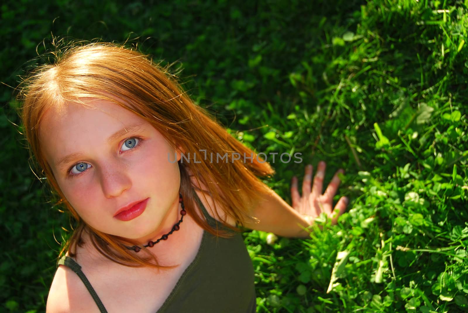 Young pretty girl sitting on green grass outside