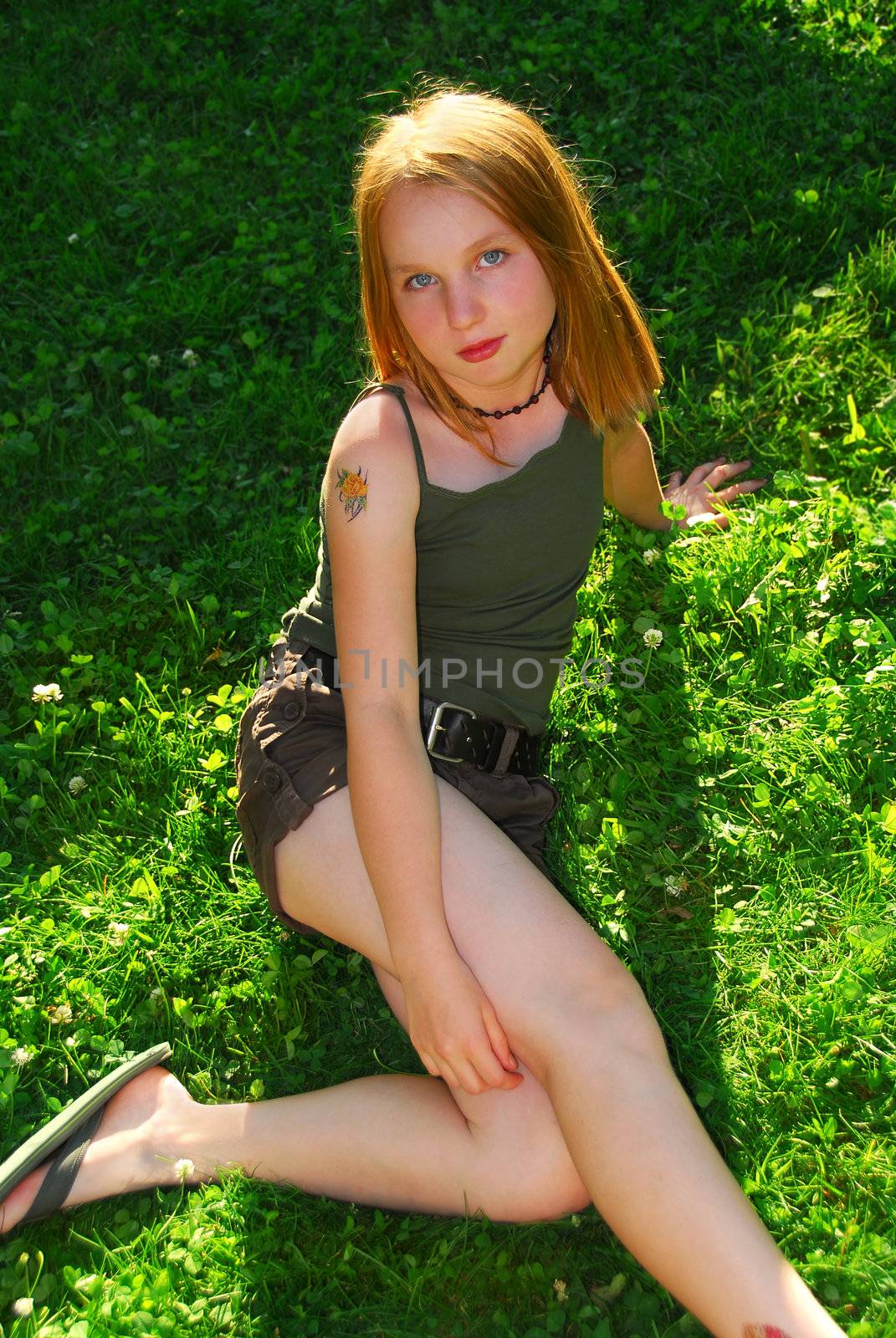 Young pretty girl sitting on green grass outside