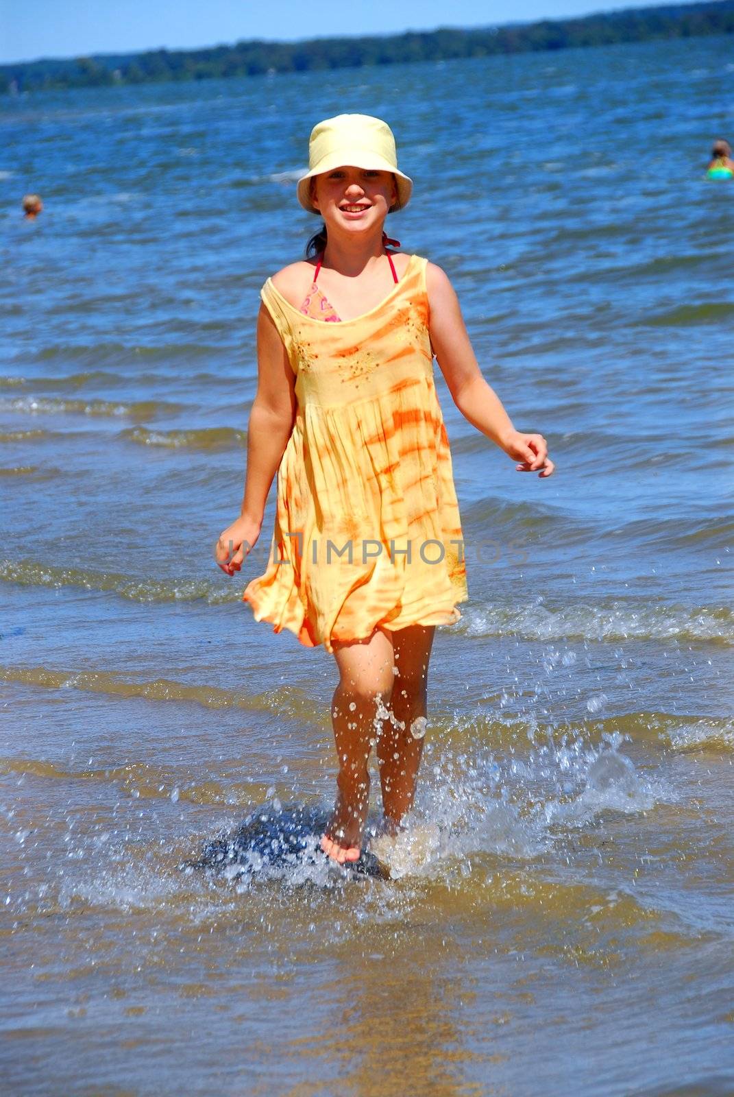 Young girl running in shallow water on a beach