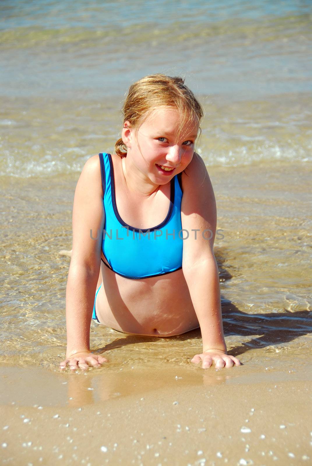 Young girl lying on a beach in shallow water