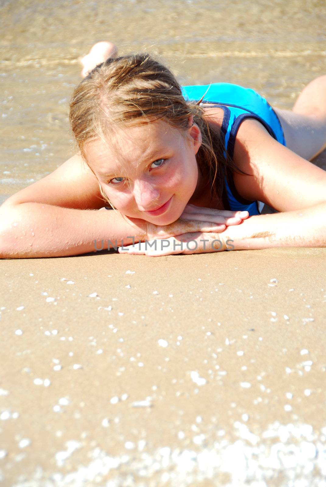 Young girl lying on a beach in shallow water