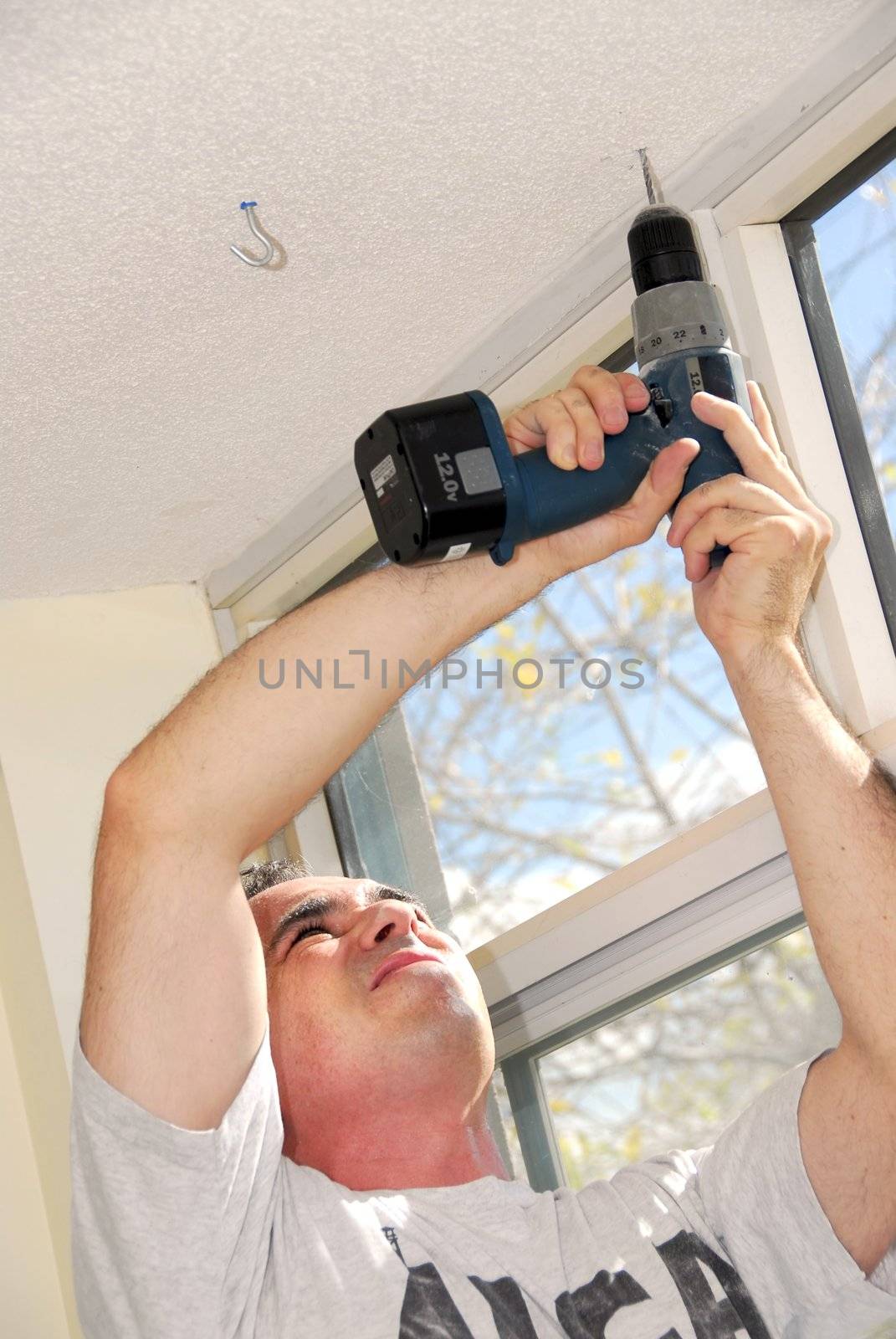 Man drilling a hole in a ceiling