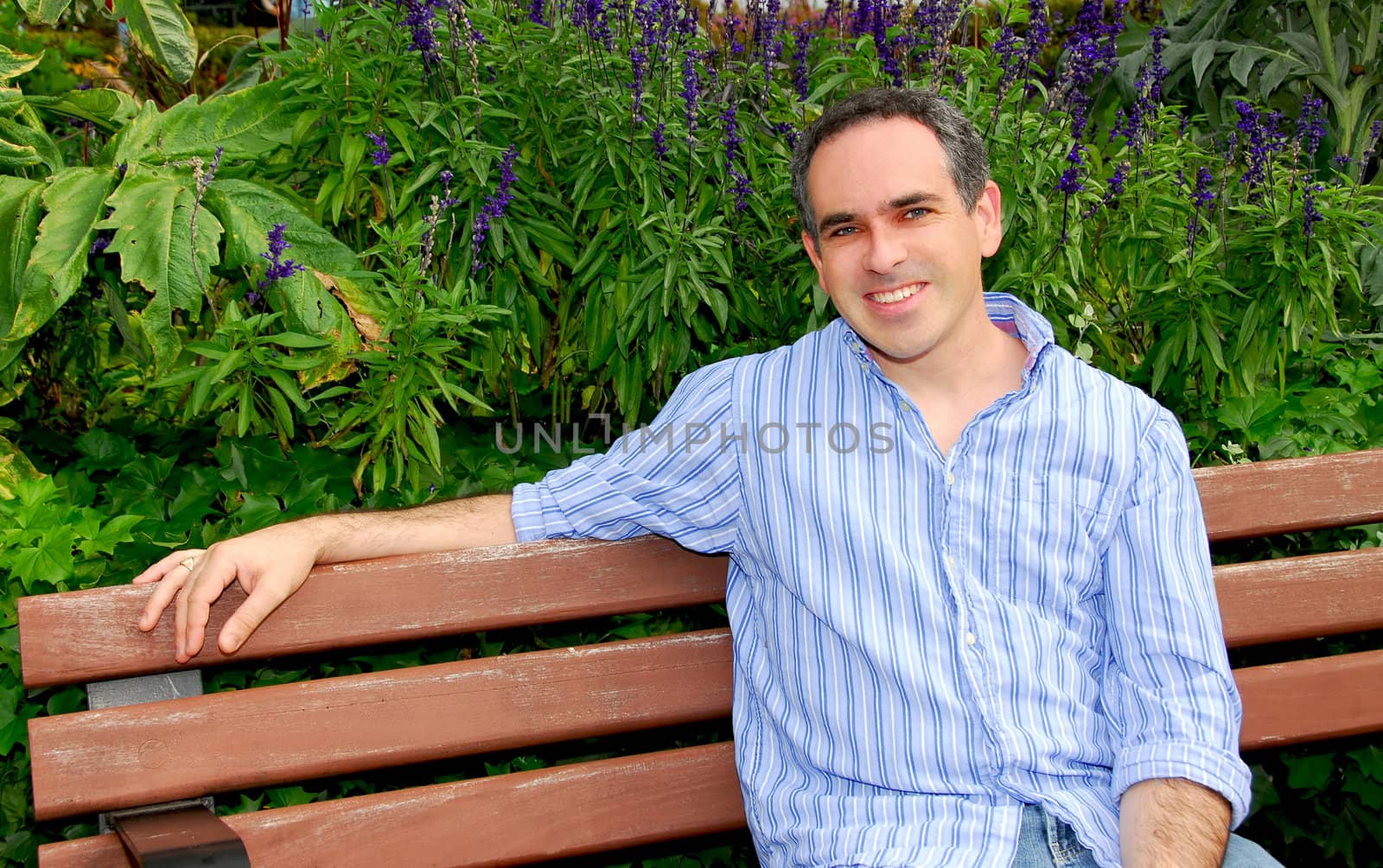 Portrait of an attractive man sitting on a pack bench