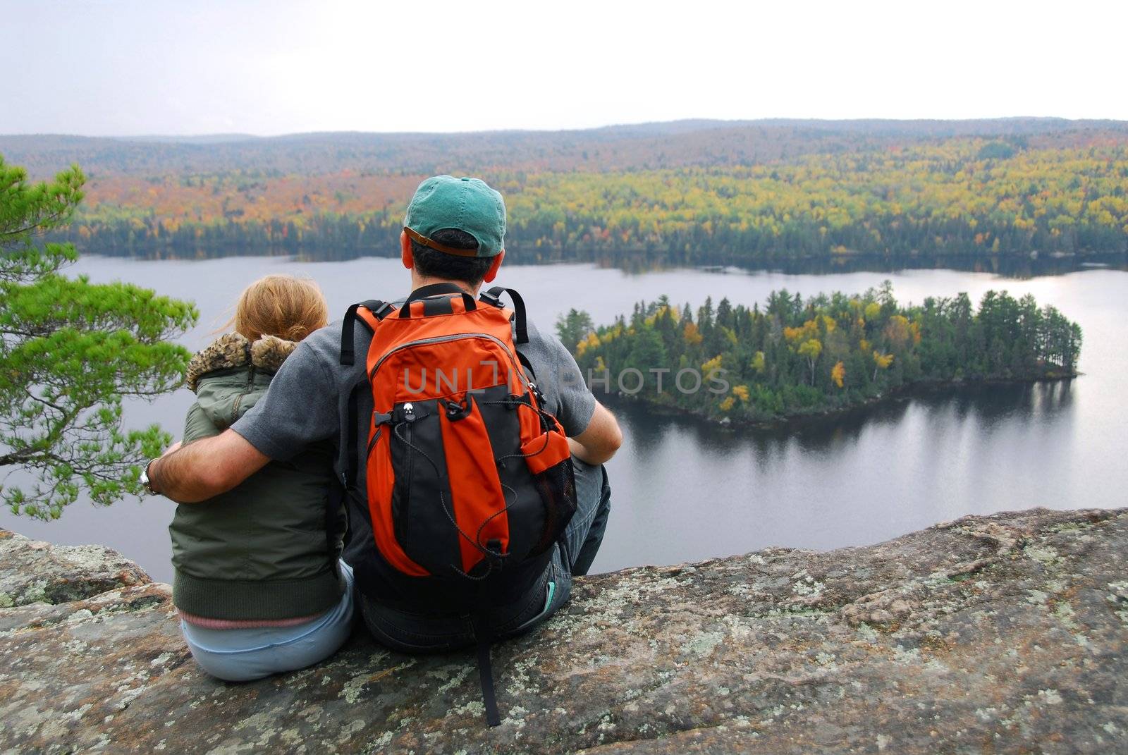 Parent and child sitting on cliff edge enjoying scenic view