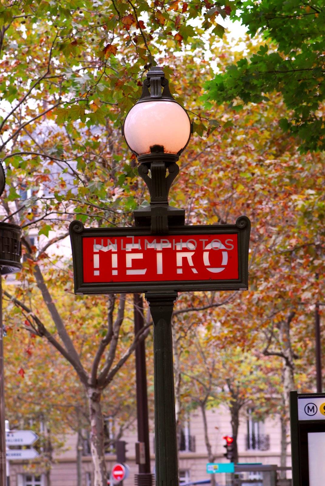 Red metro sign in Paris France on background of fall trees