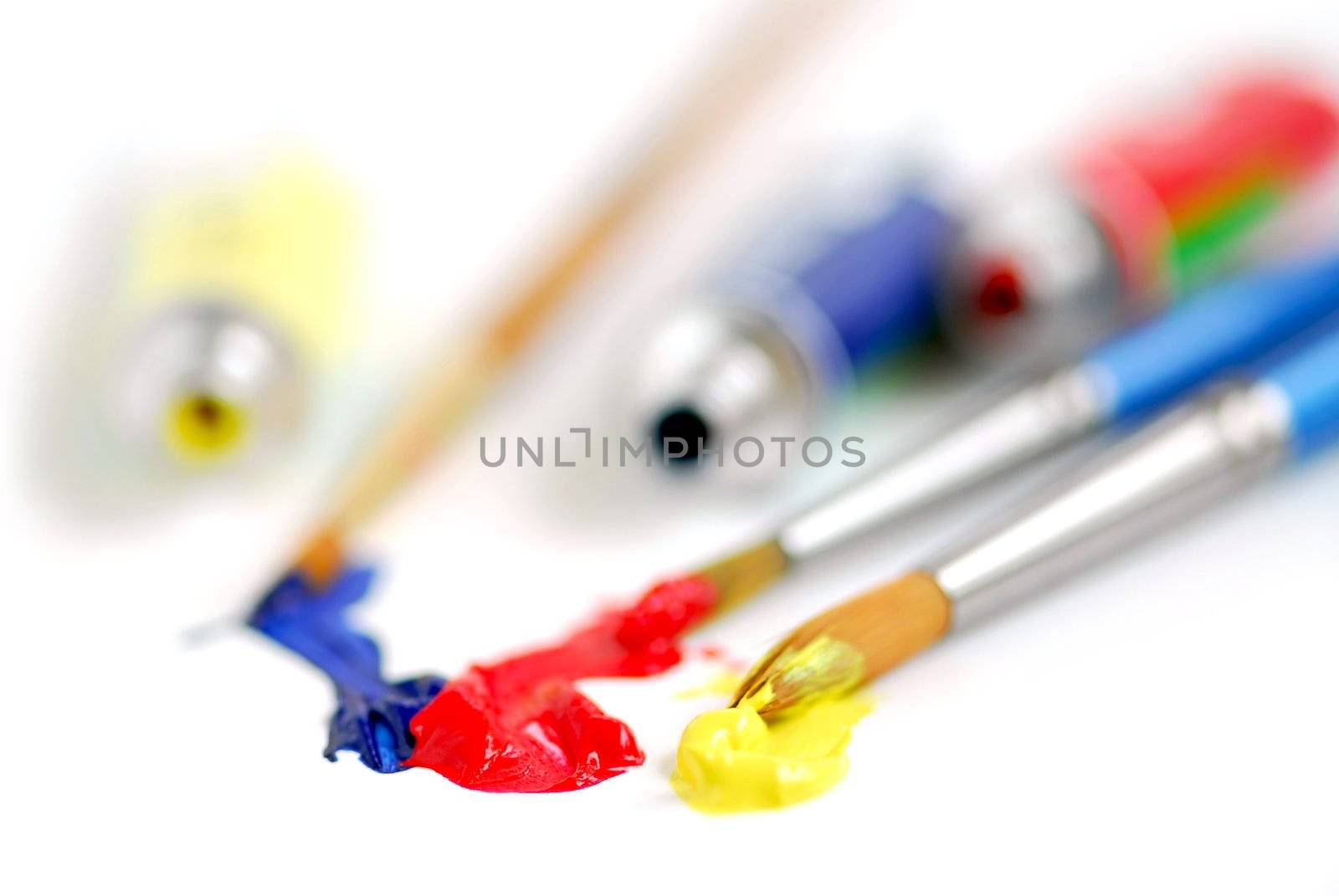 Macro of paintbrushes and paint tubes of primary colors