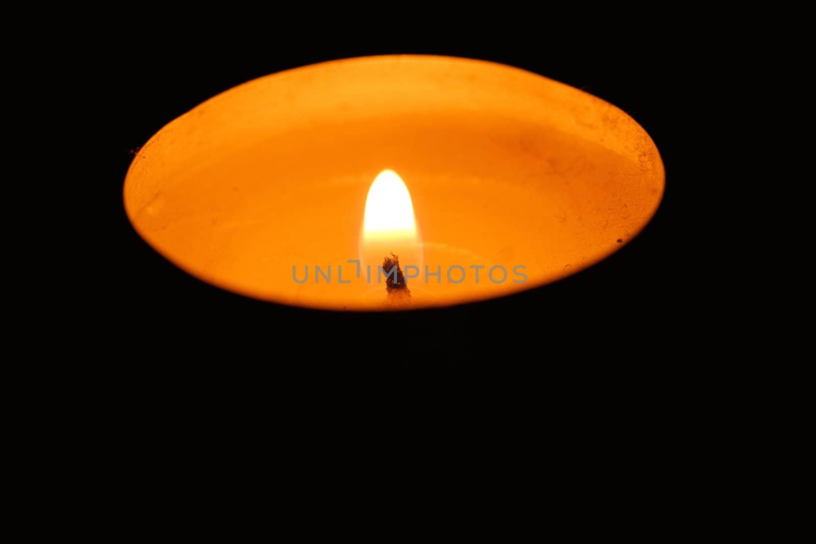 One wax candle burning in the dark