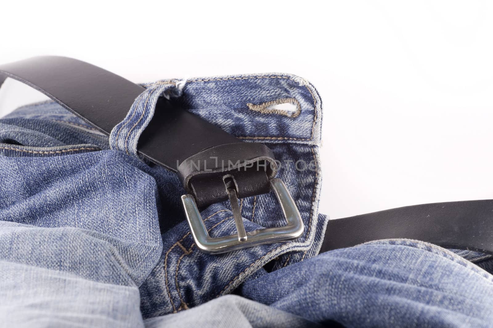Blue jeans and a black leather belt over white background