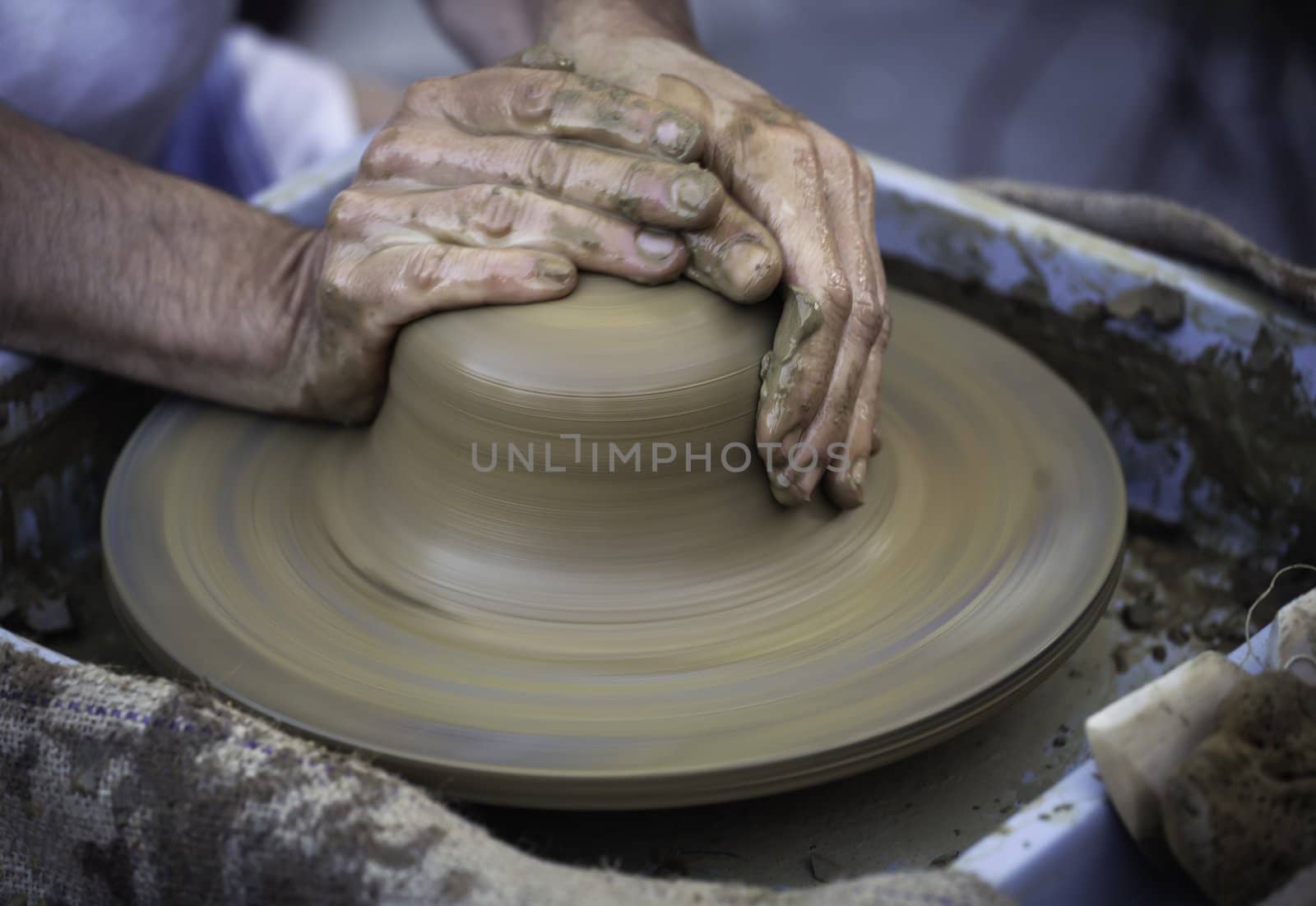 Hands working on pottery wheel , close up retro style toned photo wit shallow DOF