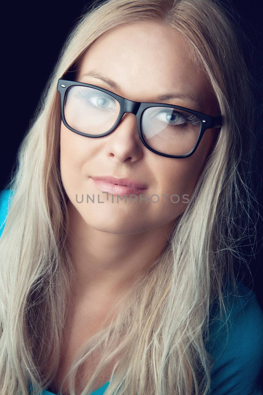 Pretty blonde wearing eyeglasses looking at the camera in the studio