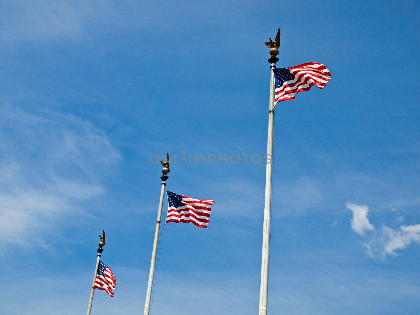 Three American Flags Waving Proudly on Tall Flagpoles