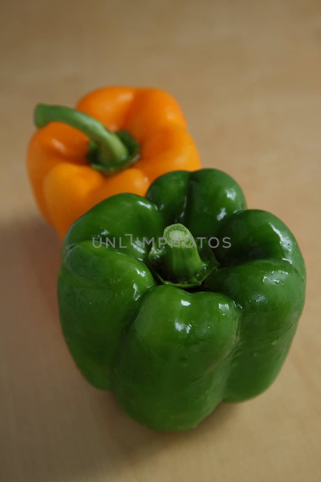 Two peppers, green and orange, on the kitchen table