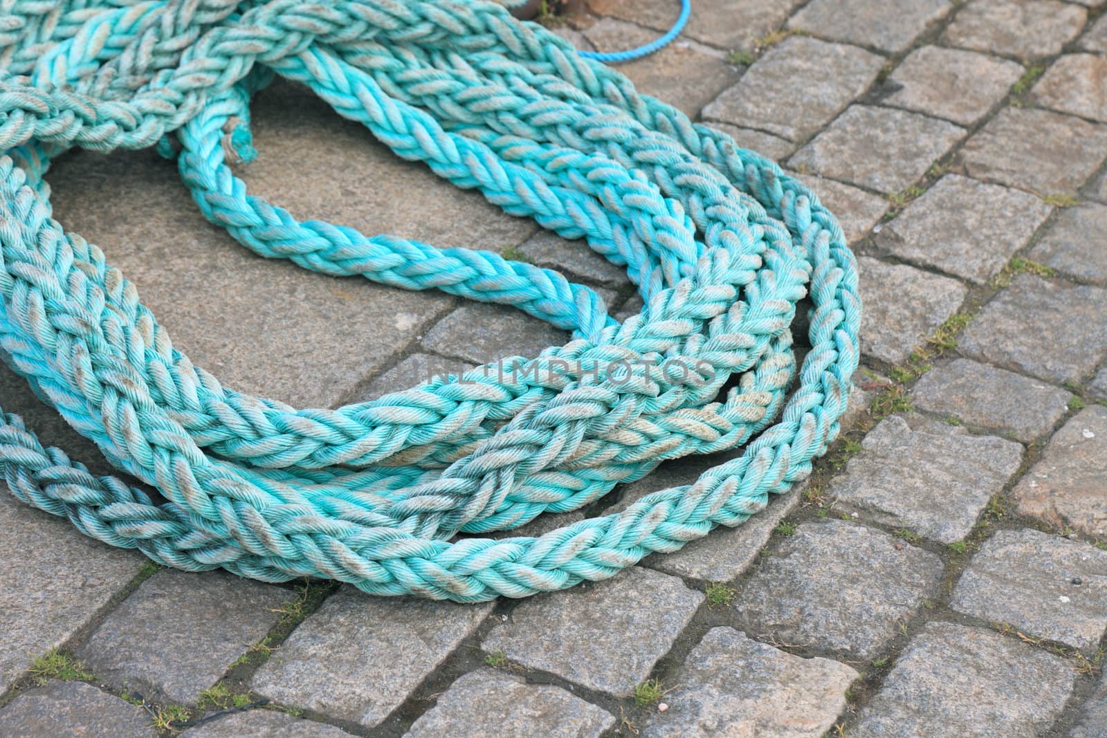 Blue twisted rope on pavement.