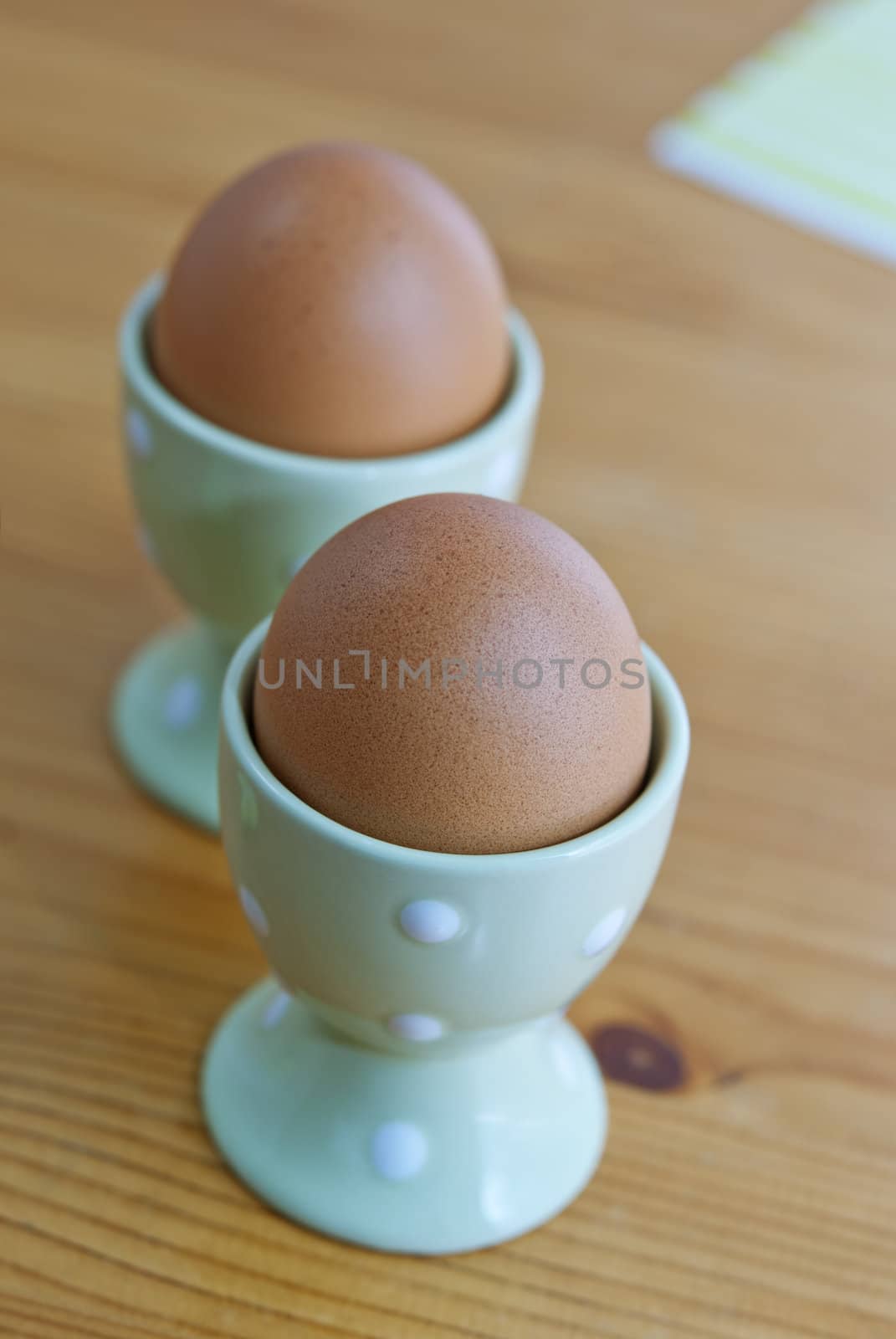 Two breakfast eggs in the egg cups on the wooden table