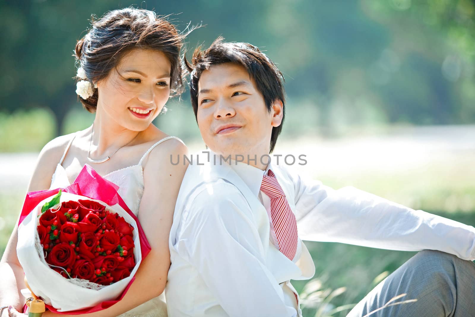 portrait of bride and groom making eye contact with rose bouquet