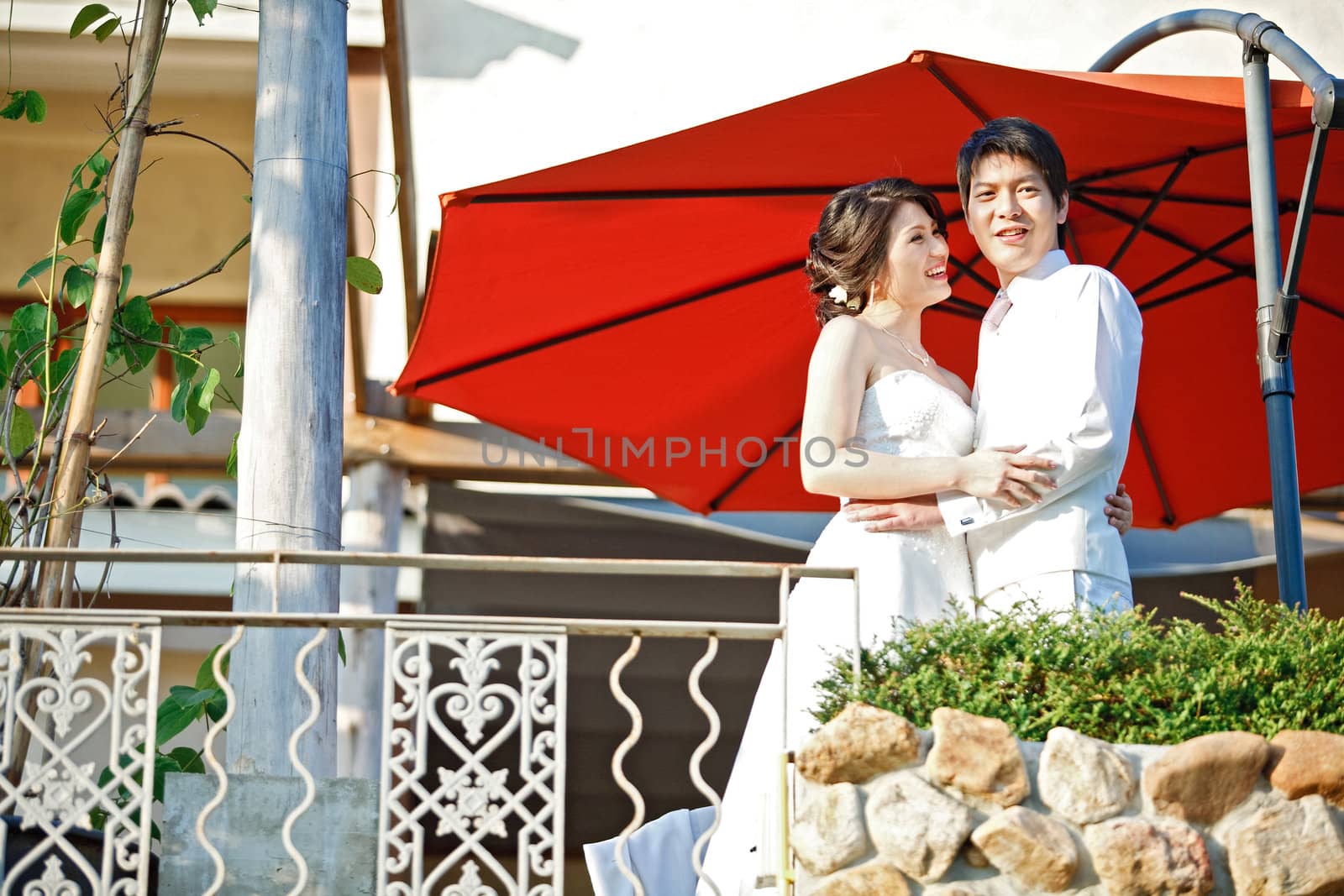 portrait of romantic bride and groom with red umbrella