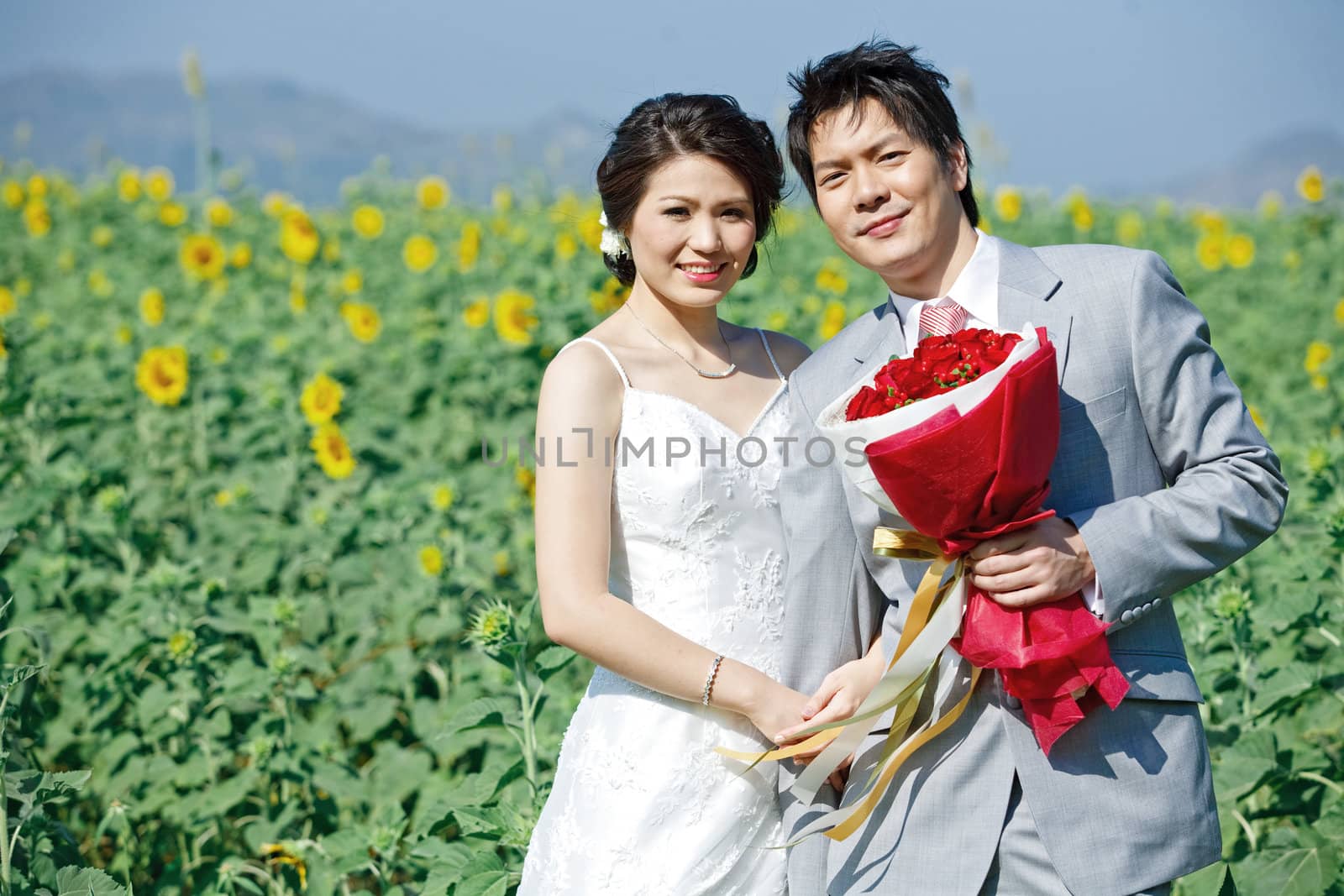 portrait of bride and groom on sunflower field by vichie81