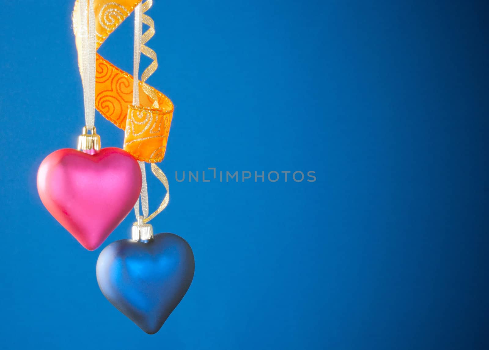 Two heart shaped toys hanging against blue background