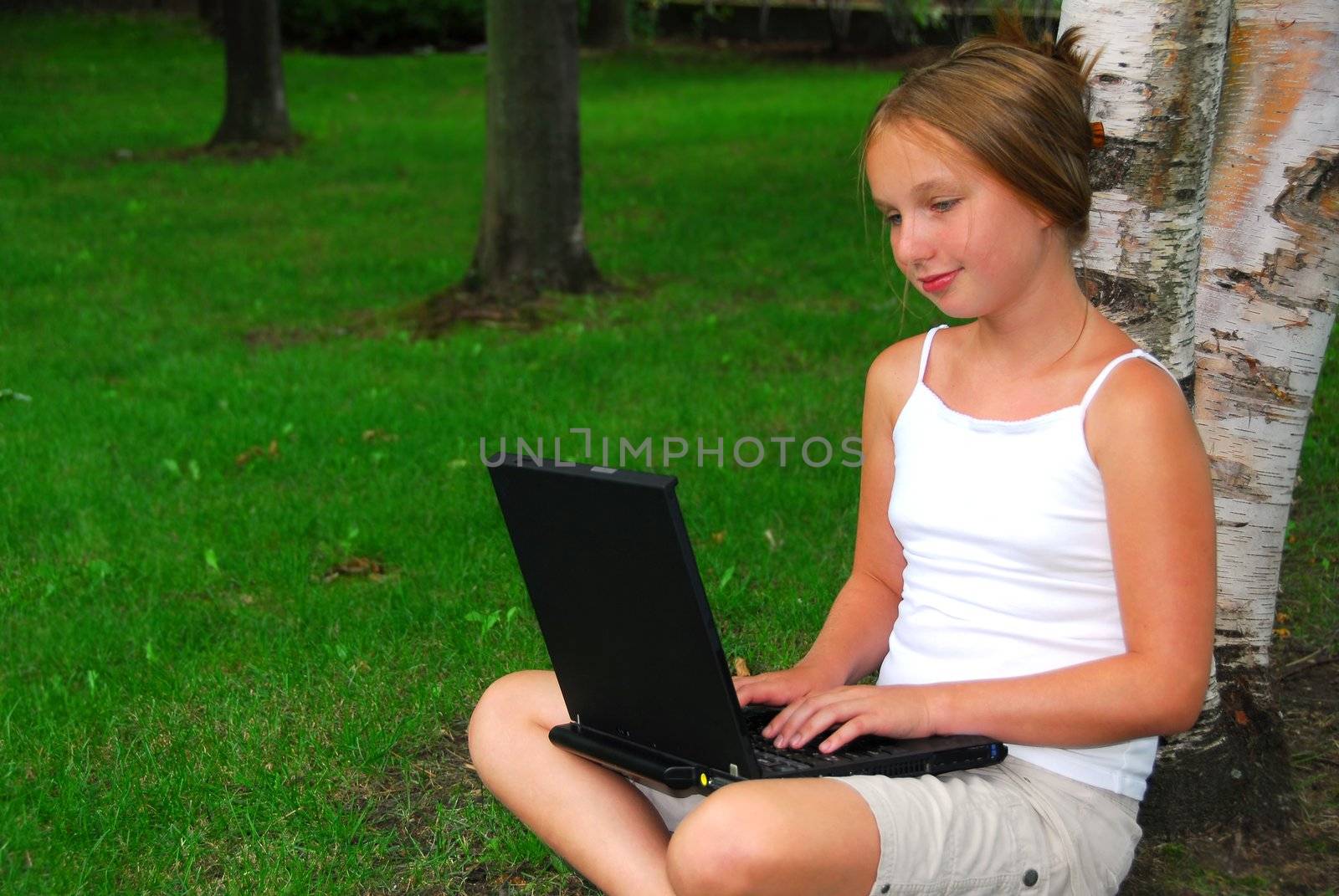 Young girl sitting in a park with laptop computer
