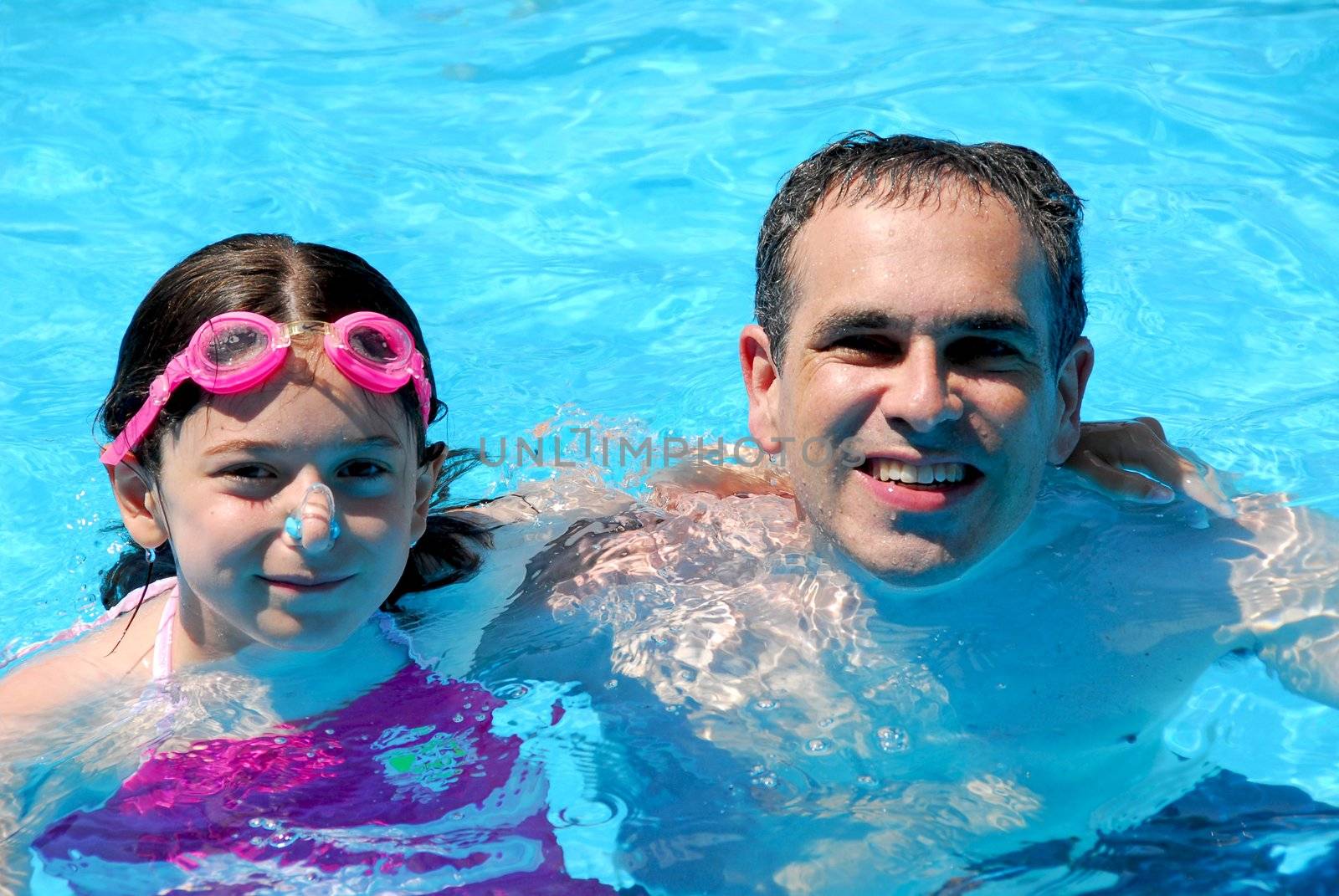Father and daughter having fun in a swimming pool