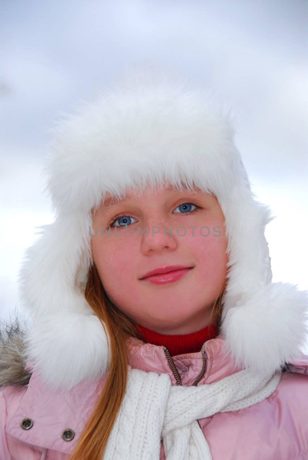 Portrait of young girl wearing white winter hat outside
