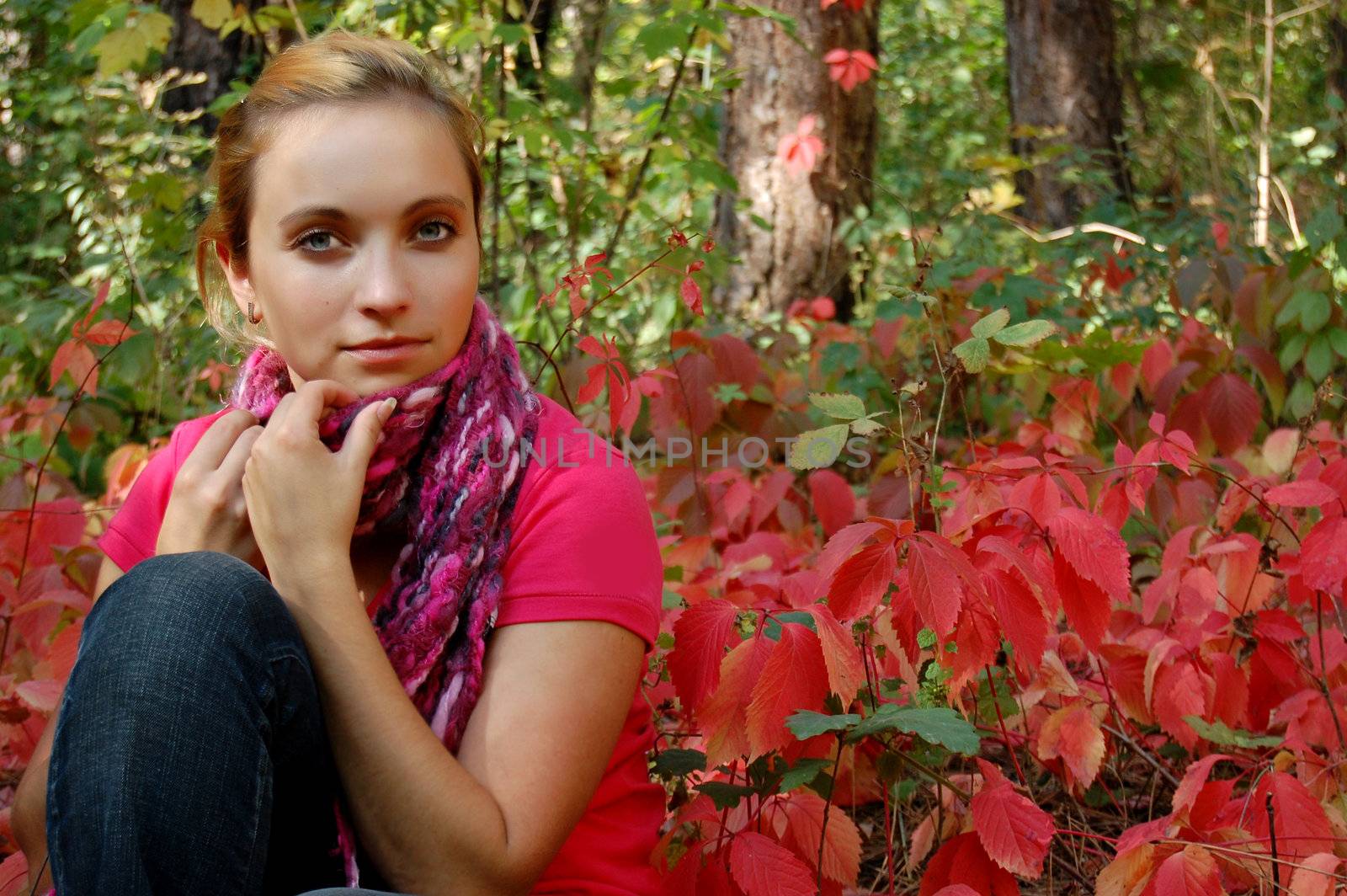 Thoughtful girl sitting in colorful autumn forest